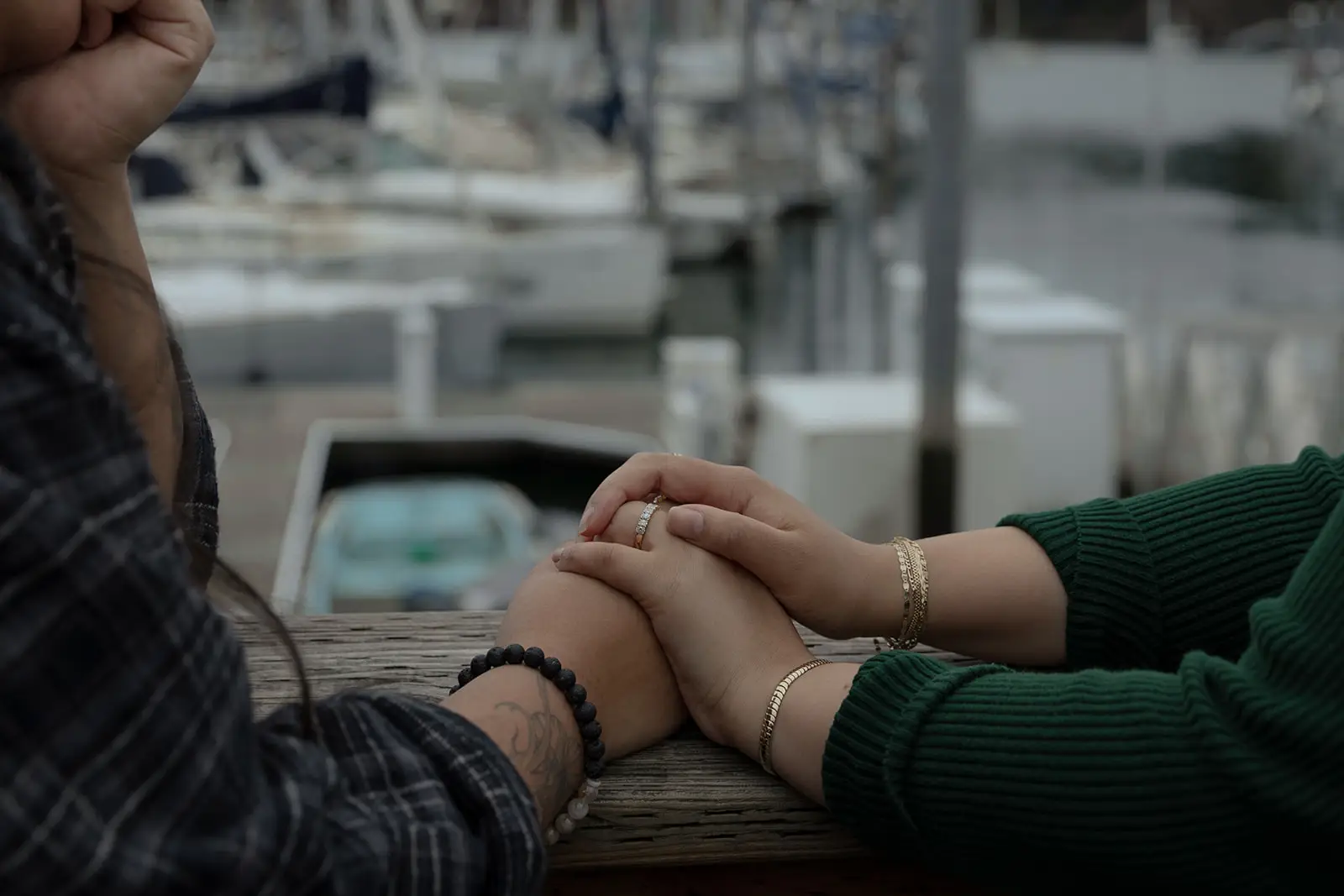 A close-up of the writer and her wife holding hands on a dock.
