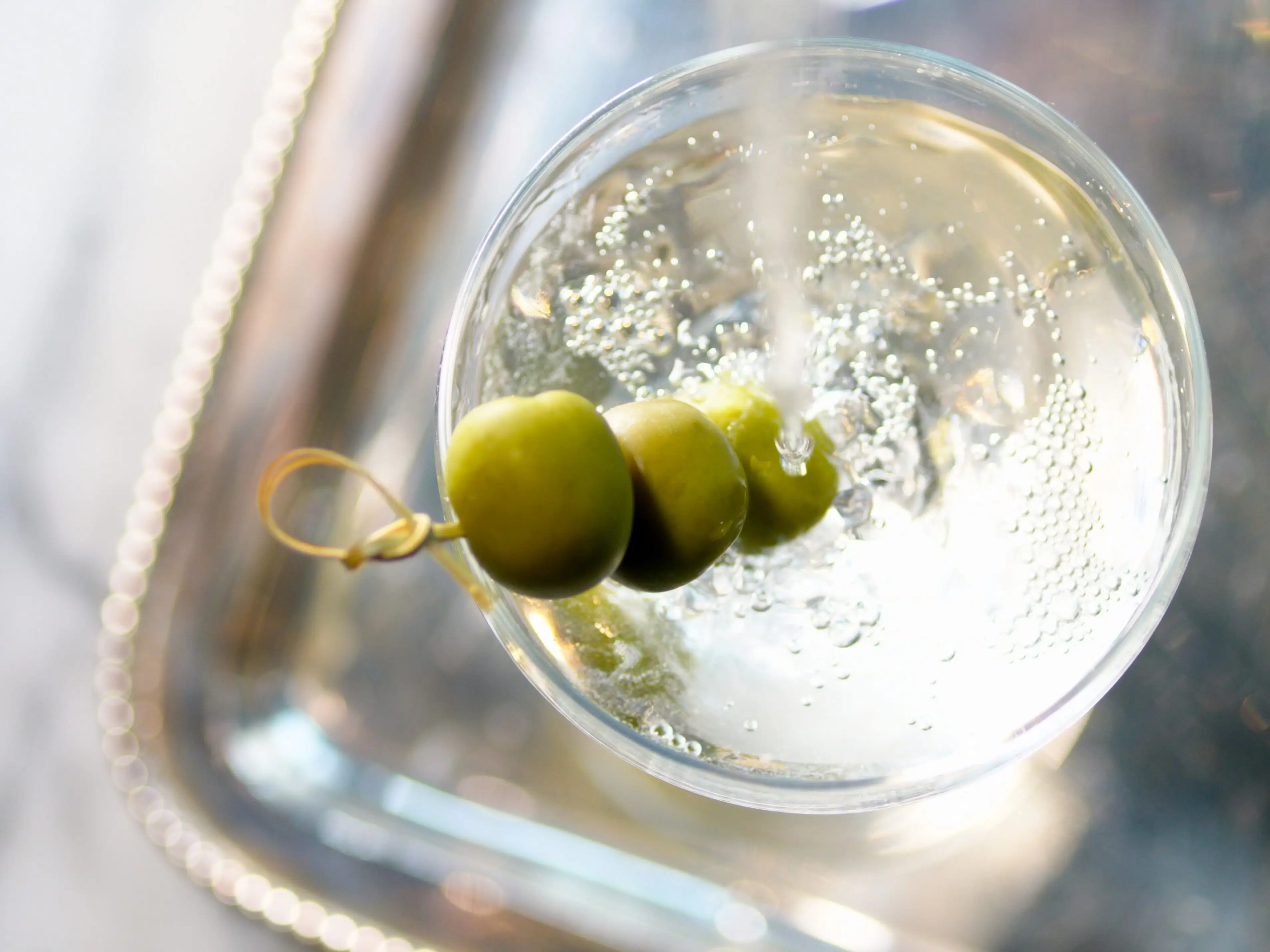 aerial view of cocktail made with gin or vodka and vermouth, with an olive garnish.