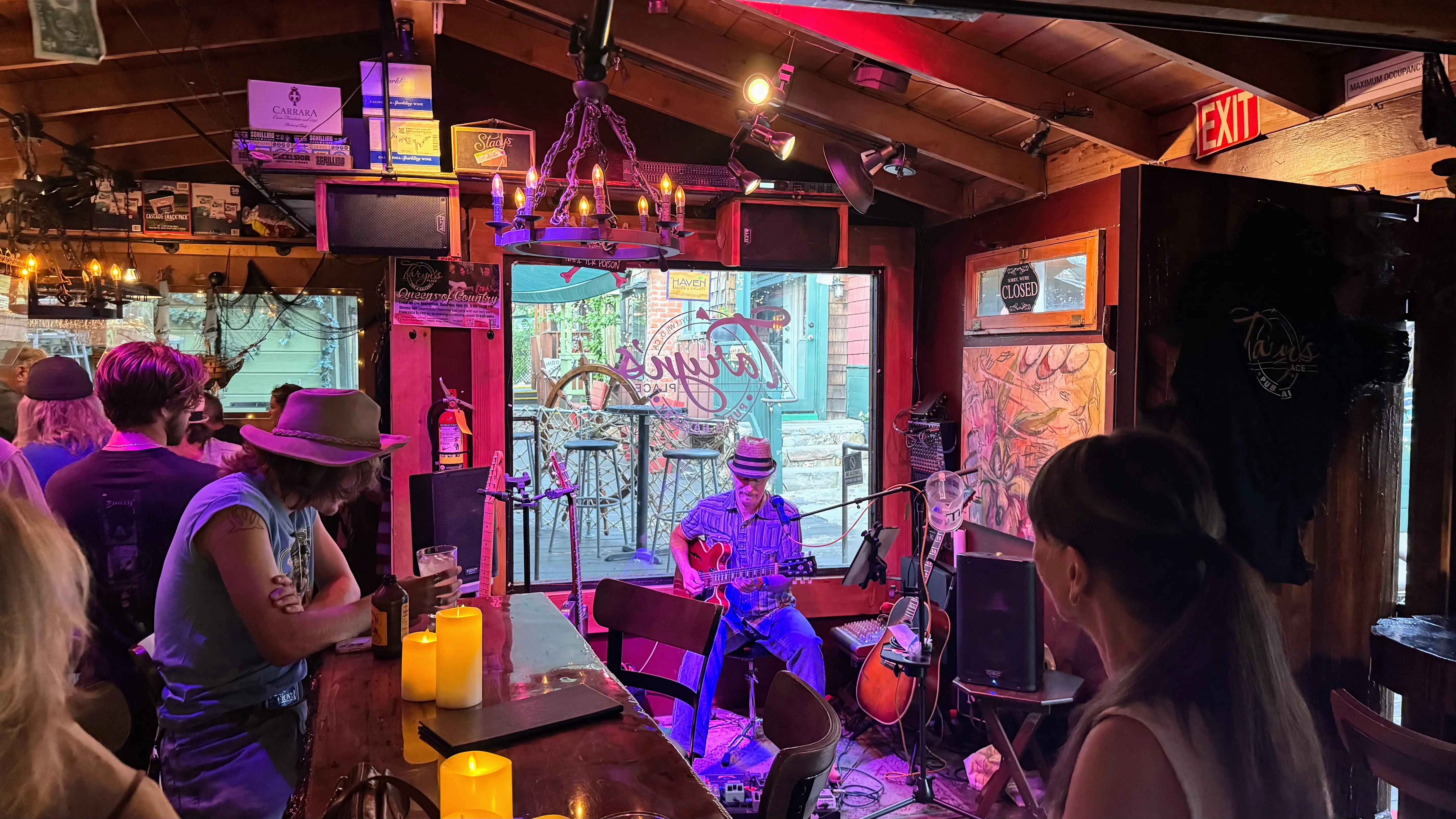 Man with guitar performing under purplish red lights