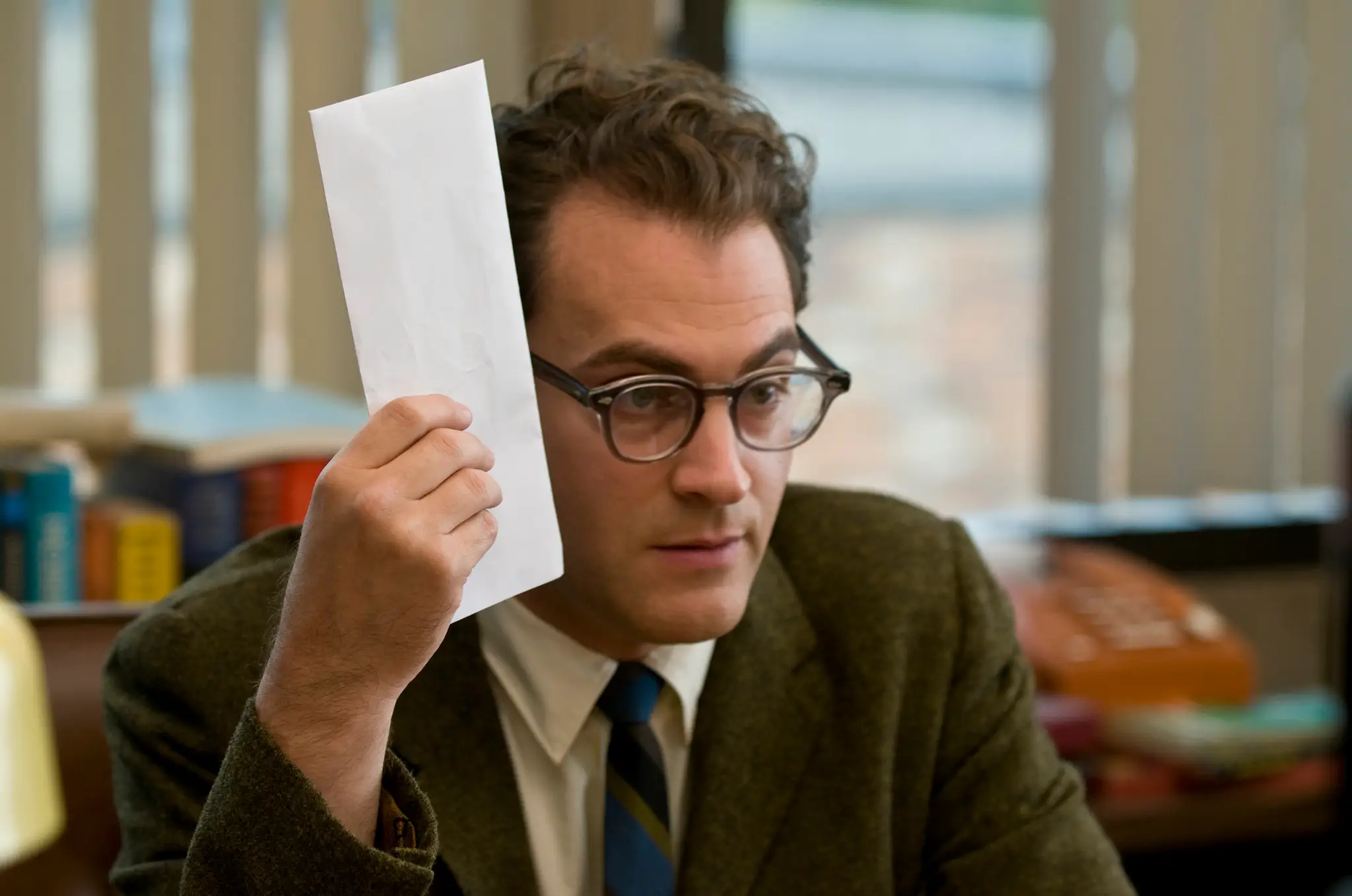 Michael Stuhlbarg holding an envelope to his head