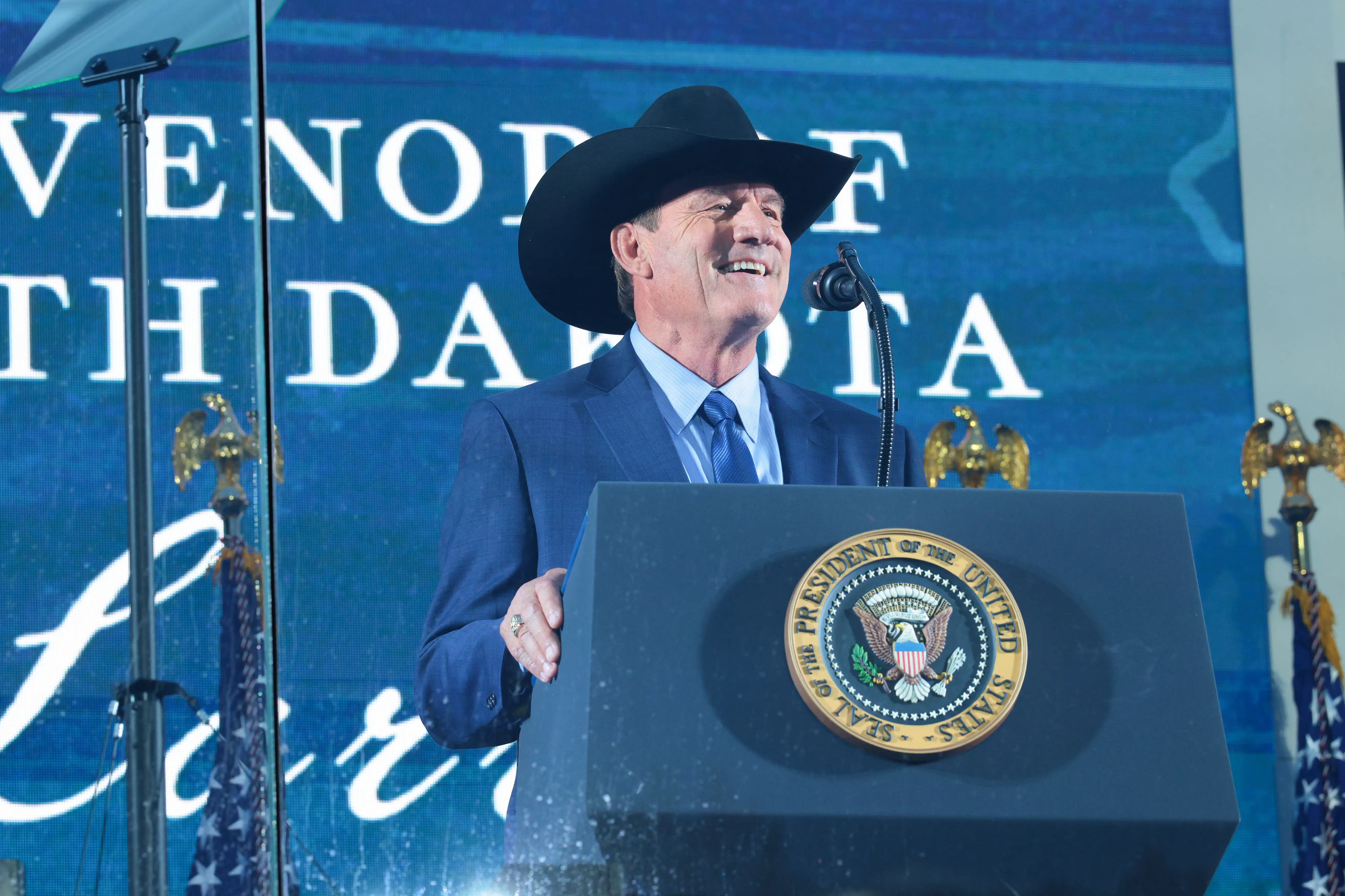 A man in a suit and cowboy hat speaks.