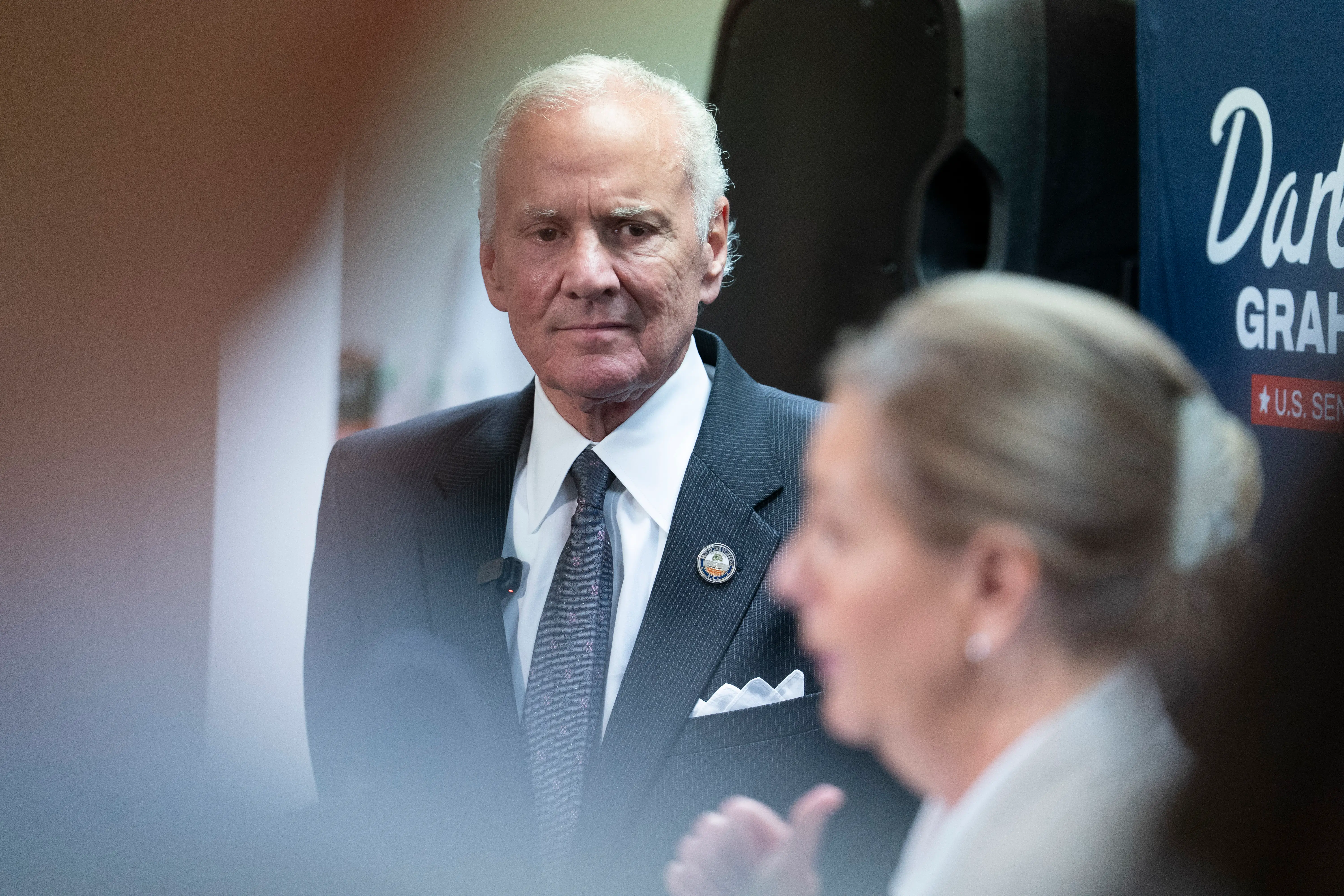 A man in a suit listens to a woman speak.