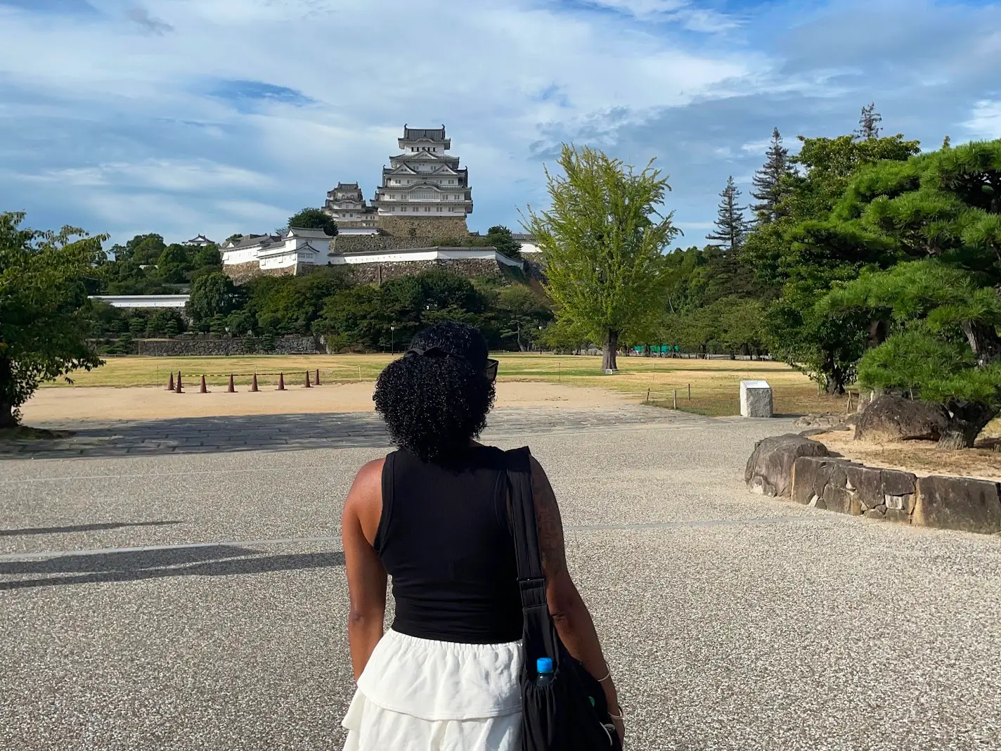 Woman looking away from camera toward temple, trees in Japan