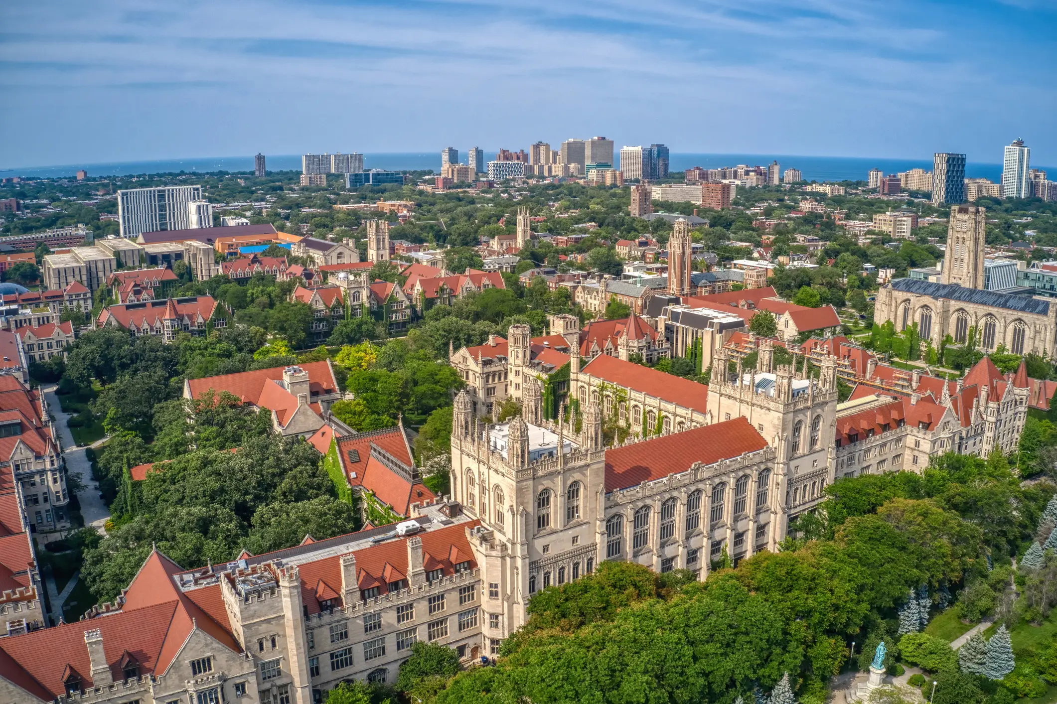 Aerial view of Gothic campus buildings at the University of Chicago with Lake Michigan and city towers beyond.