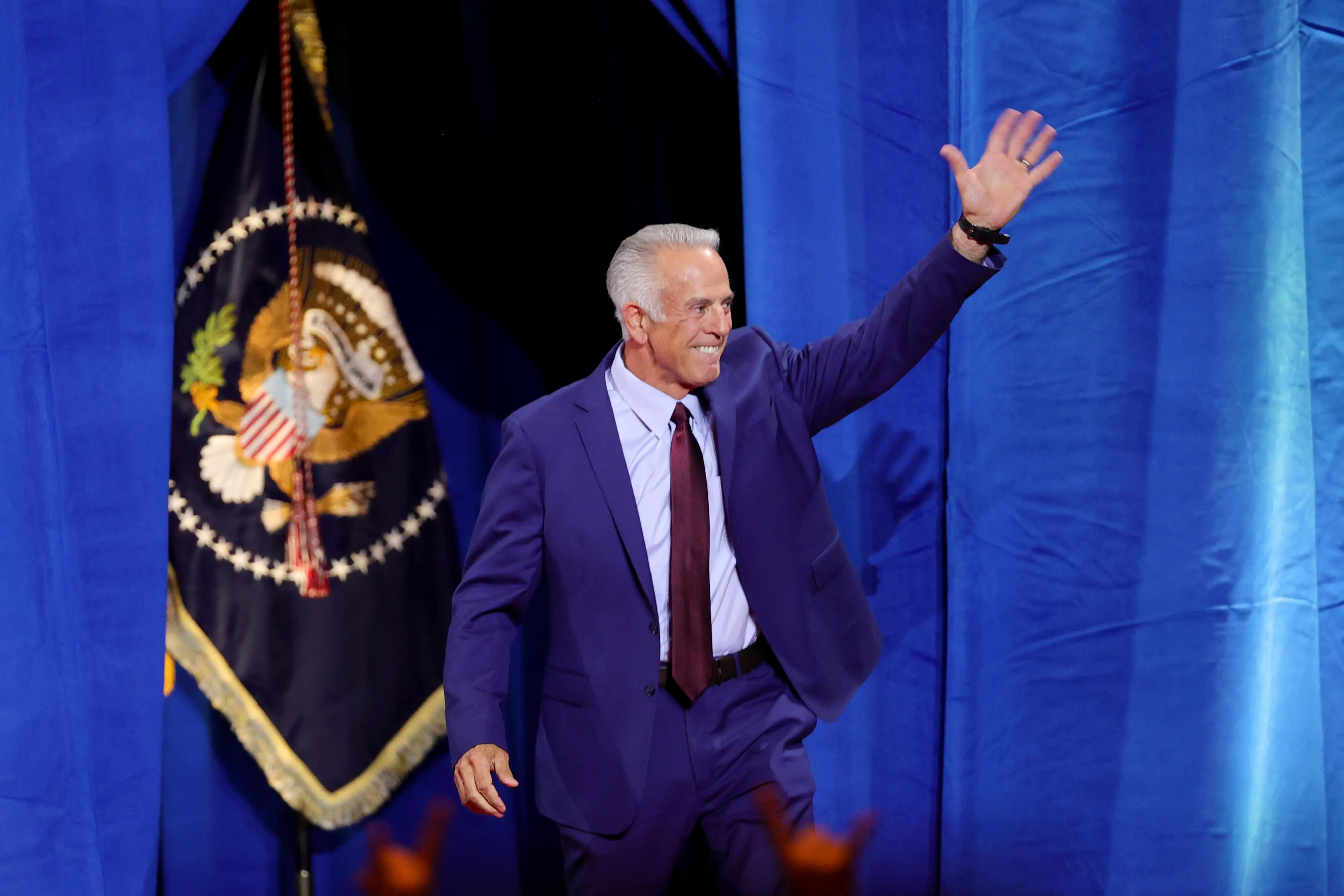 A man in a suit waves.