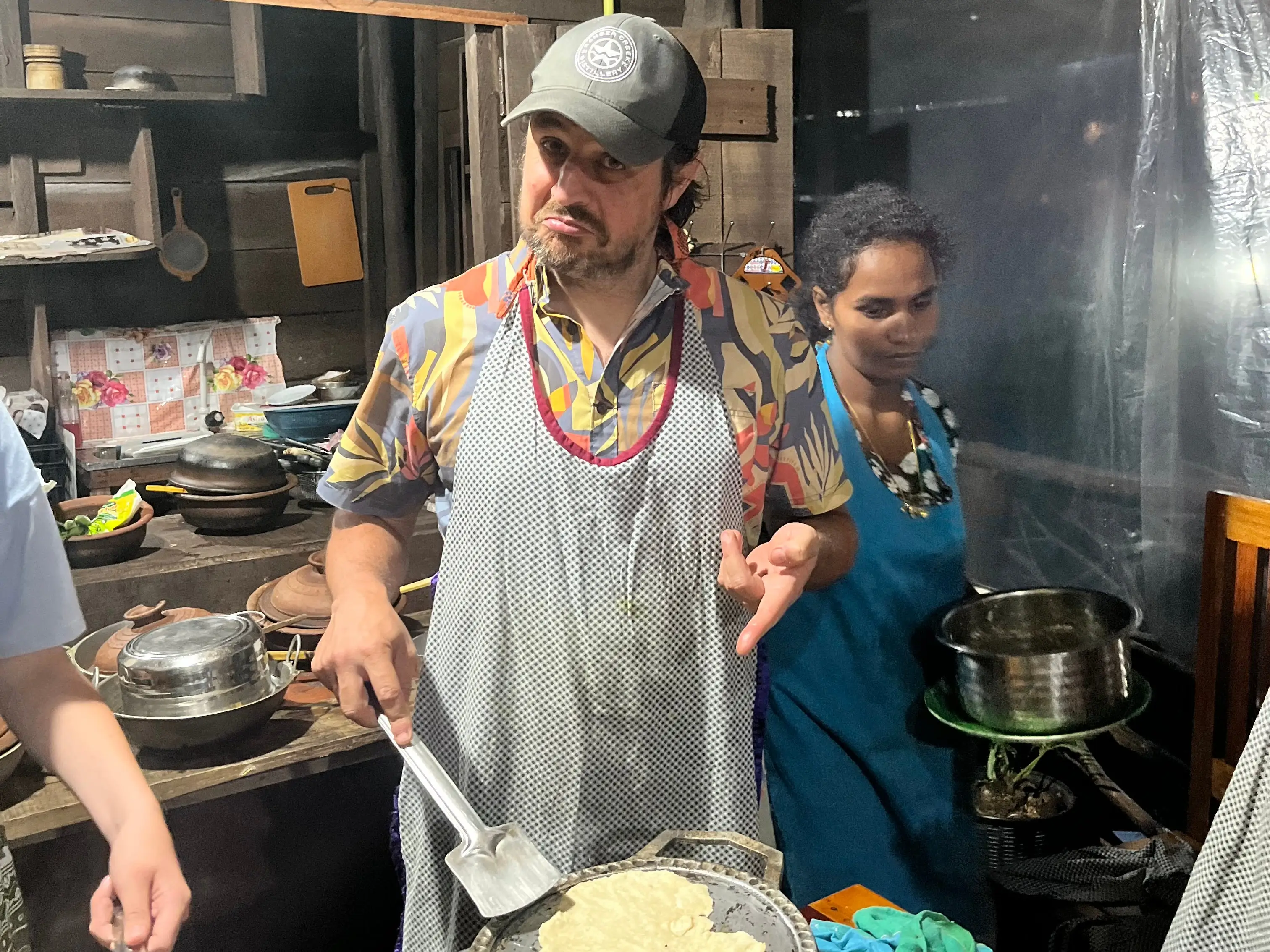 Man in apron at cooking class making roti