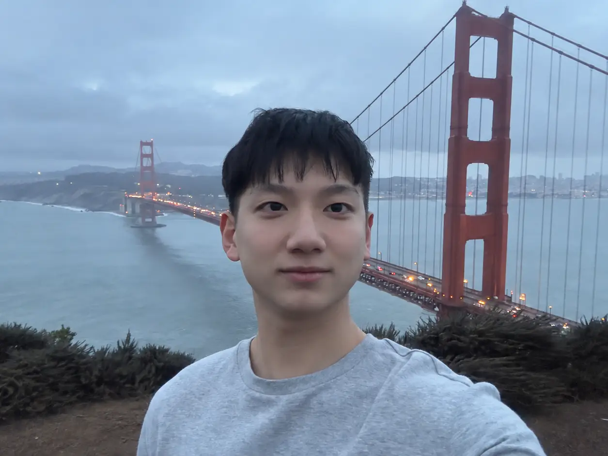 A man standing in front of the Golden Gate bridge in San Francisco on a foggy day.