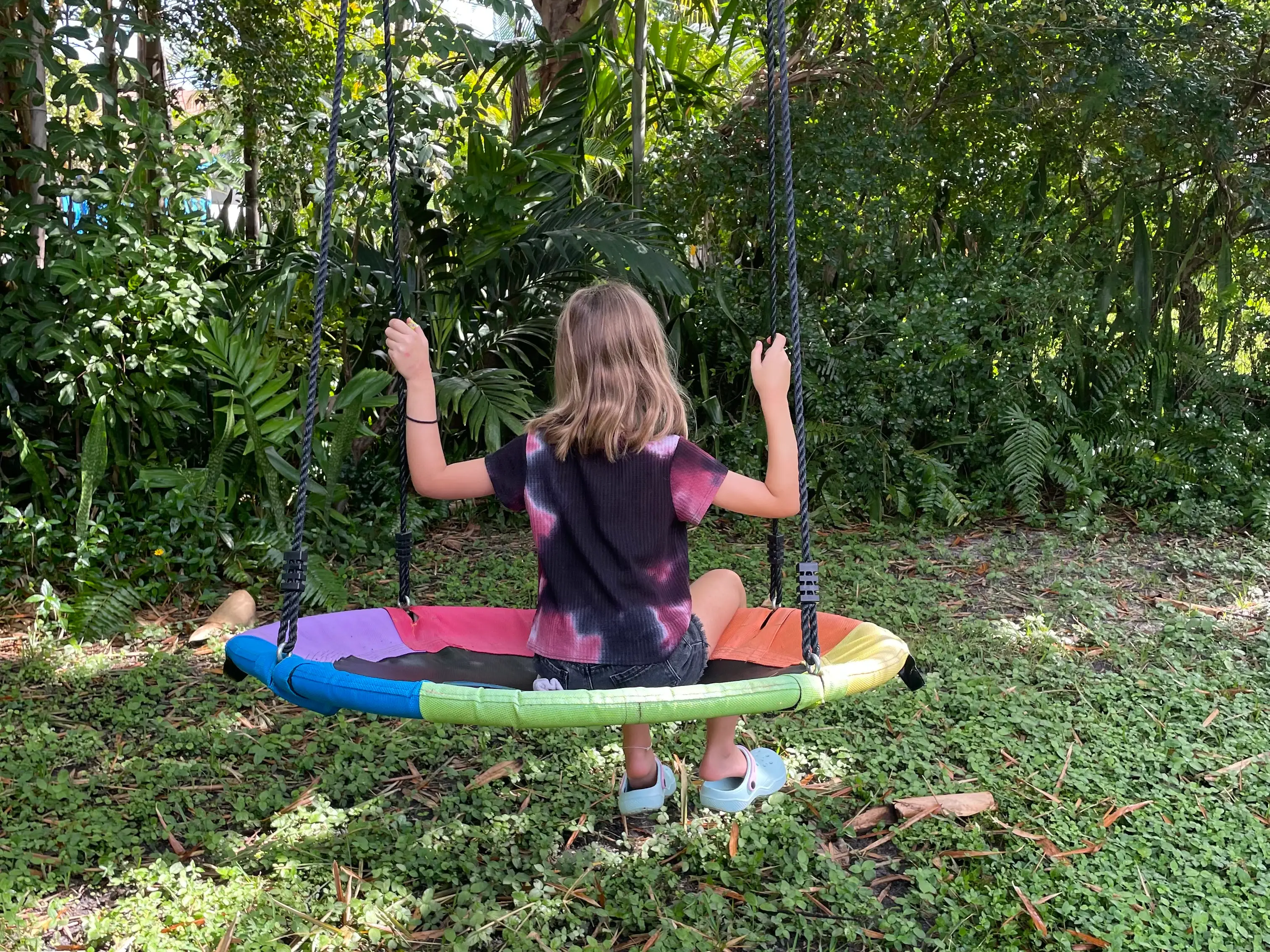 the author's daughter sitting on a colorful swing hanging from a tree