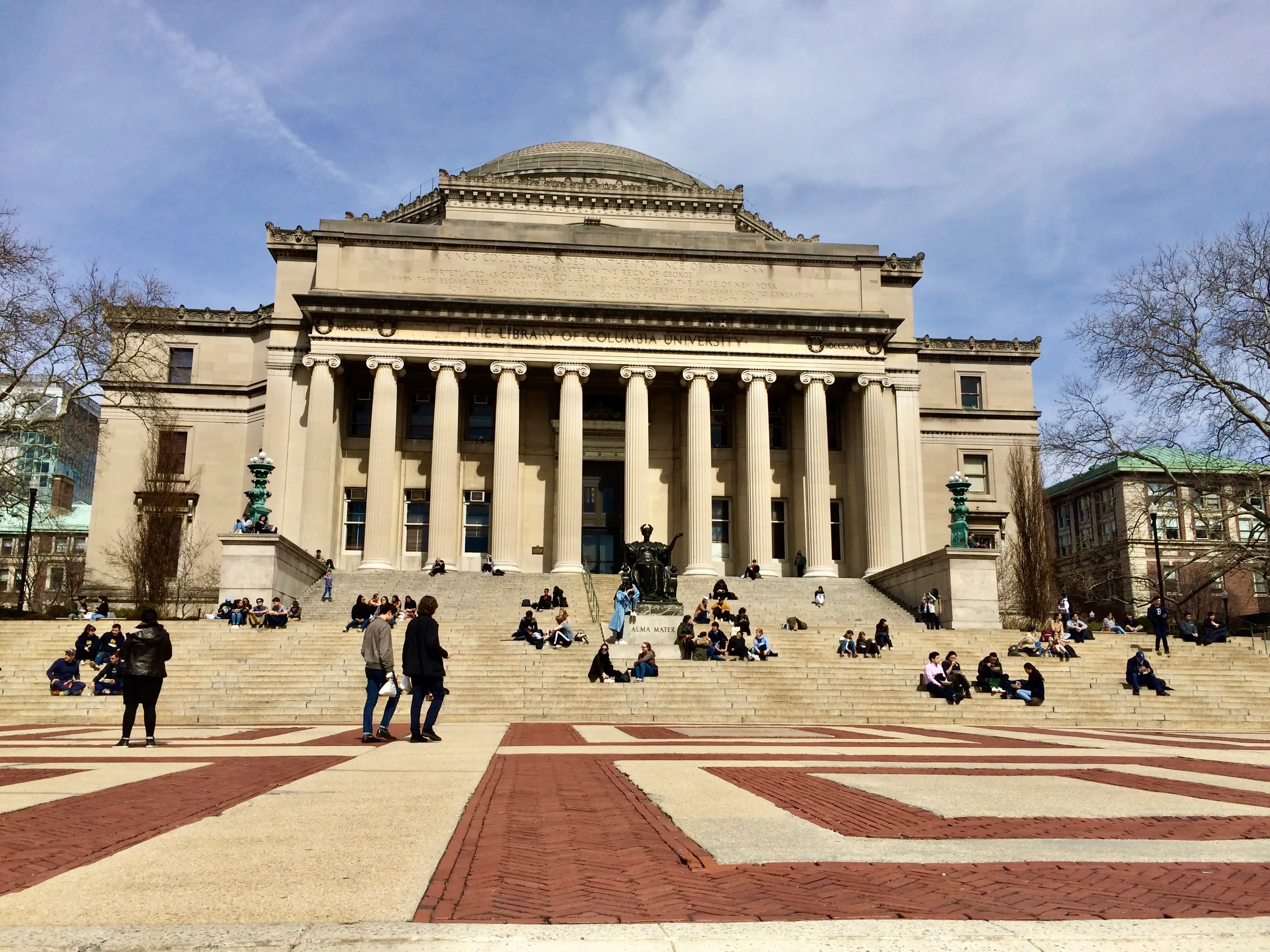 People sit on the steps outside Columbia University’s Low Memorial Library beneath the Alma Mater statue.