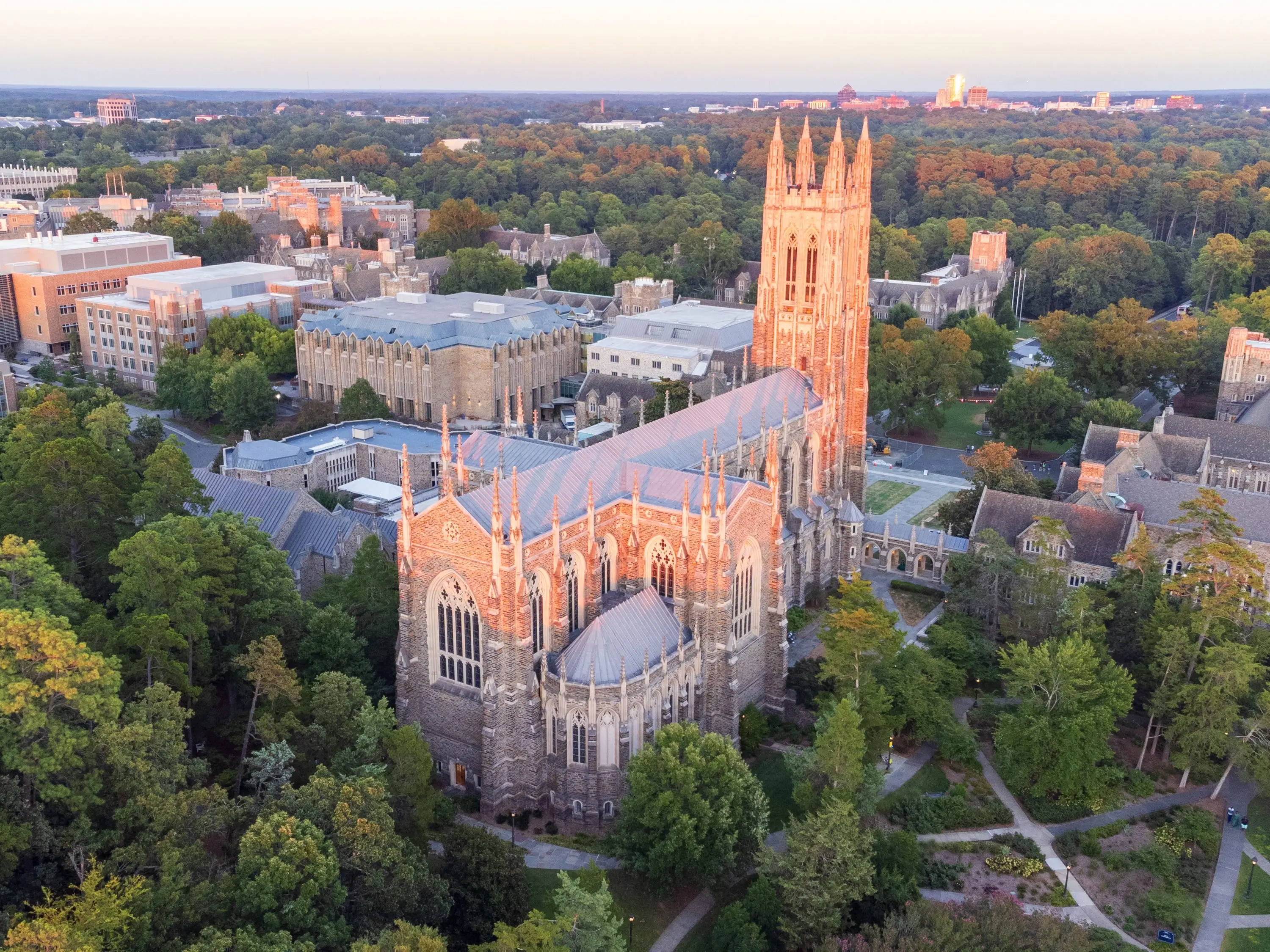 Aerial view of Duke University Chapel and surrounding Gothic campus buildings at sunset.