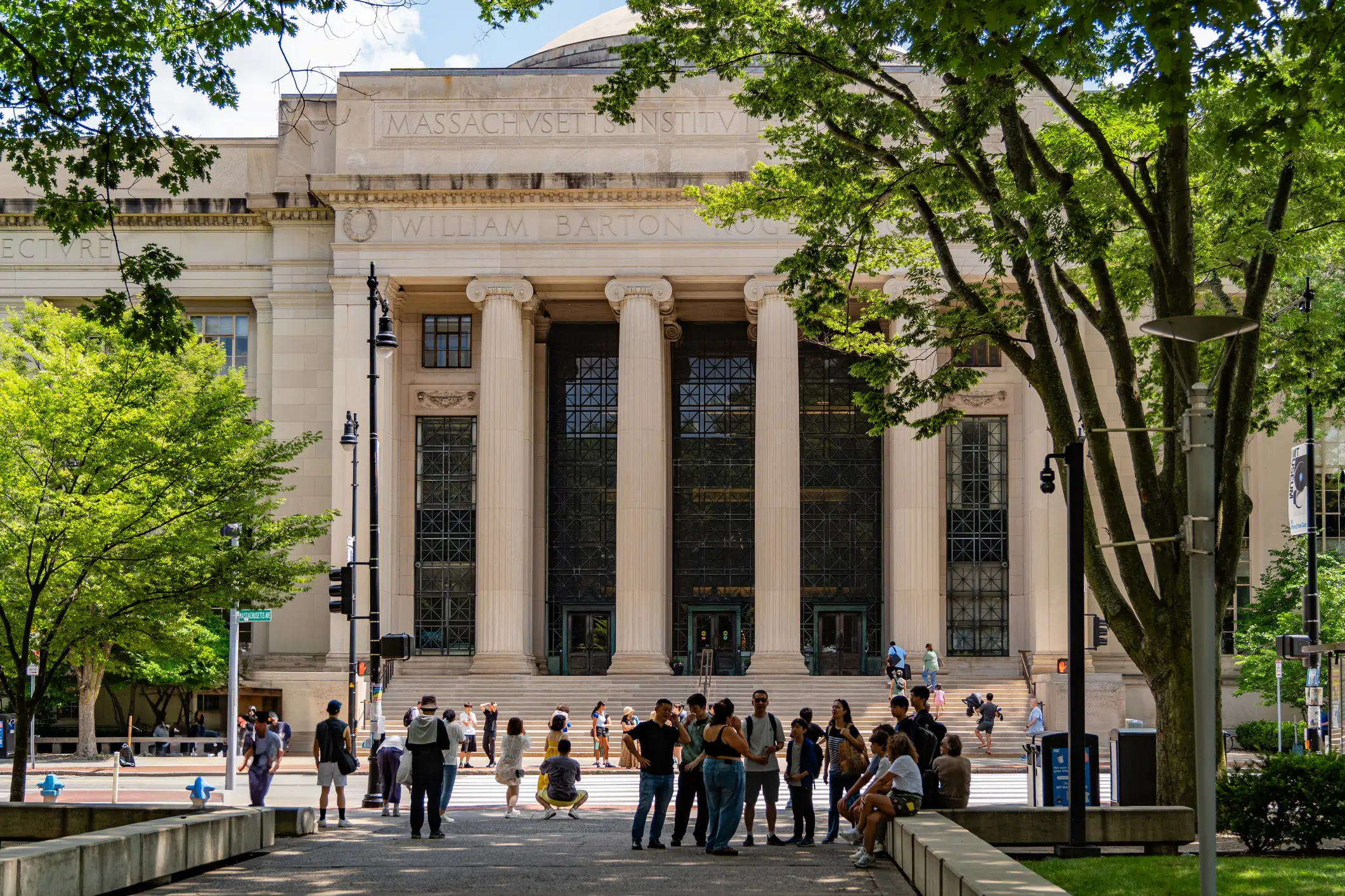 People gather outside the columned entrance of Massachusetts Institute of Technology's William Barton Rogers Building.