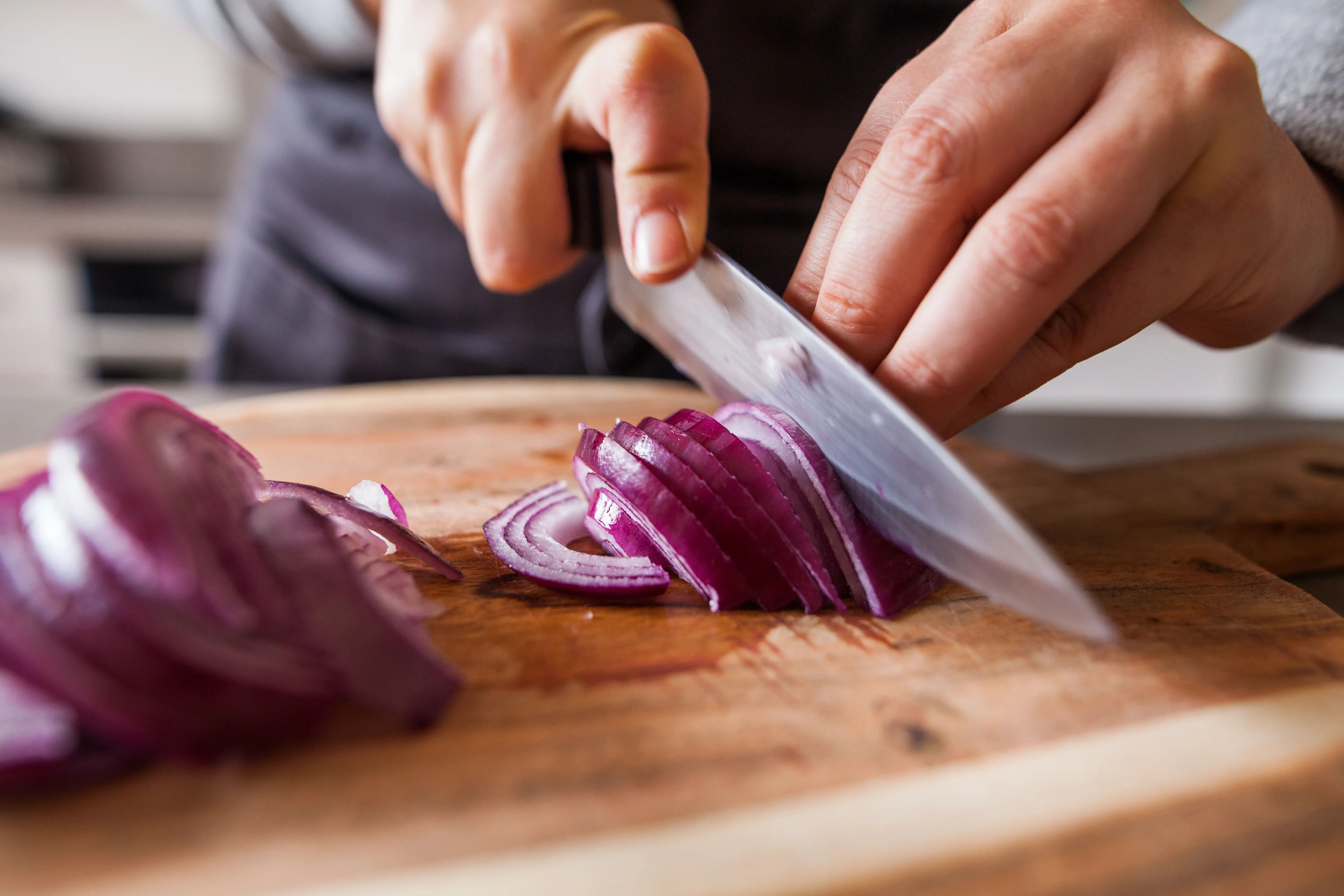Person chopping red onion with sharp knife