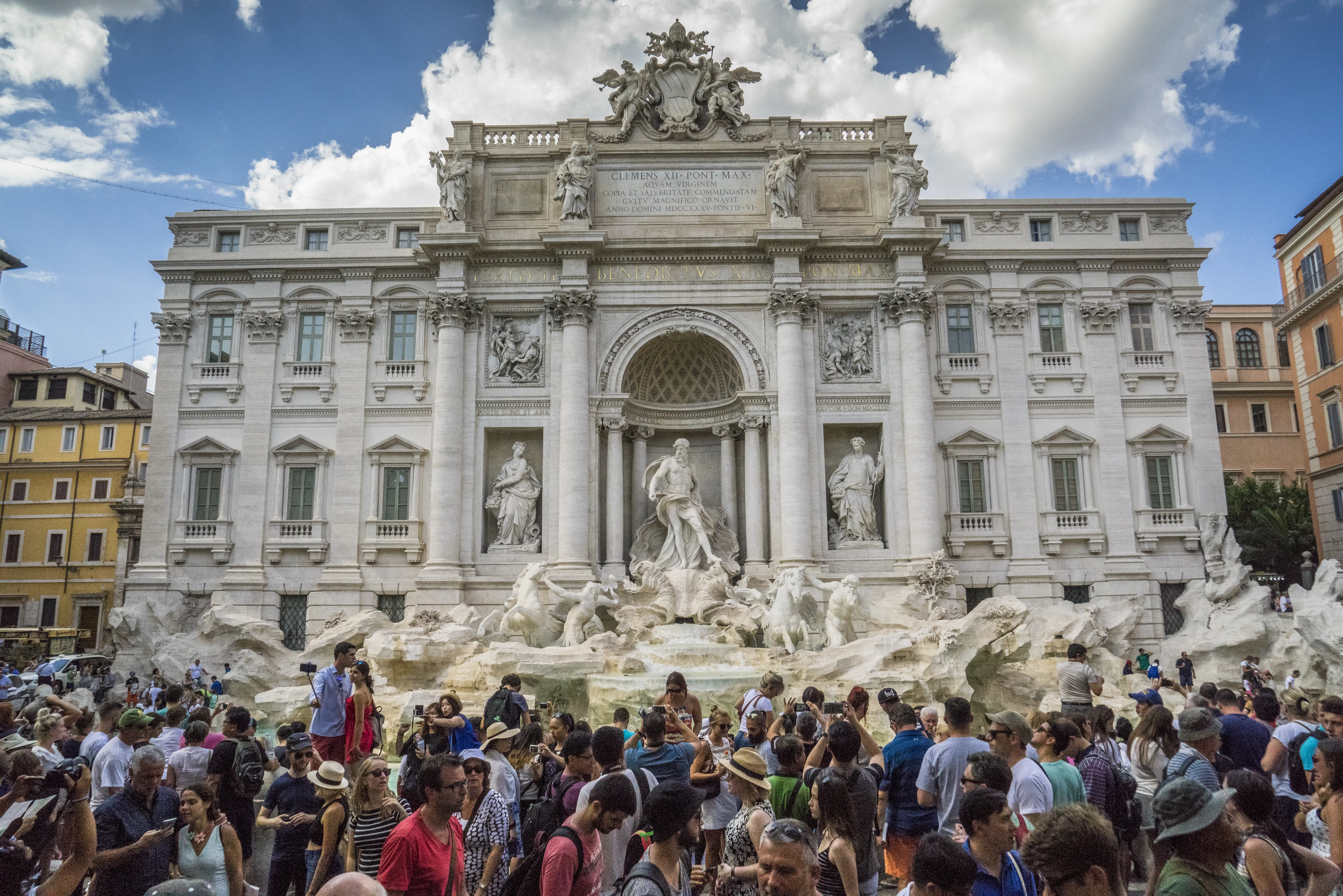 Crowds stand in front of the Trevi Fountain in Italy.