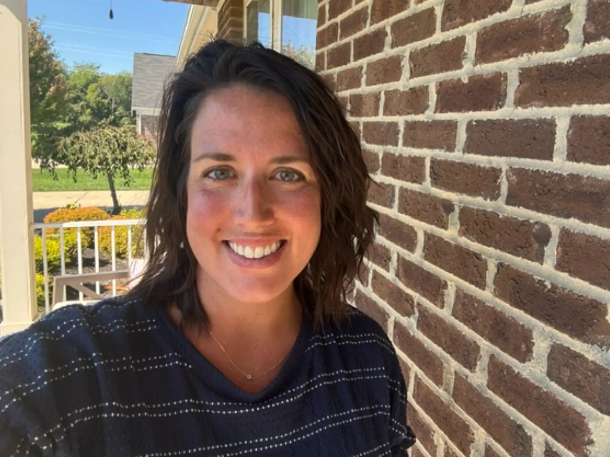 Woman smiling next to brick wall in selfie