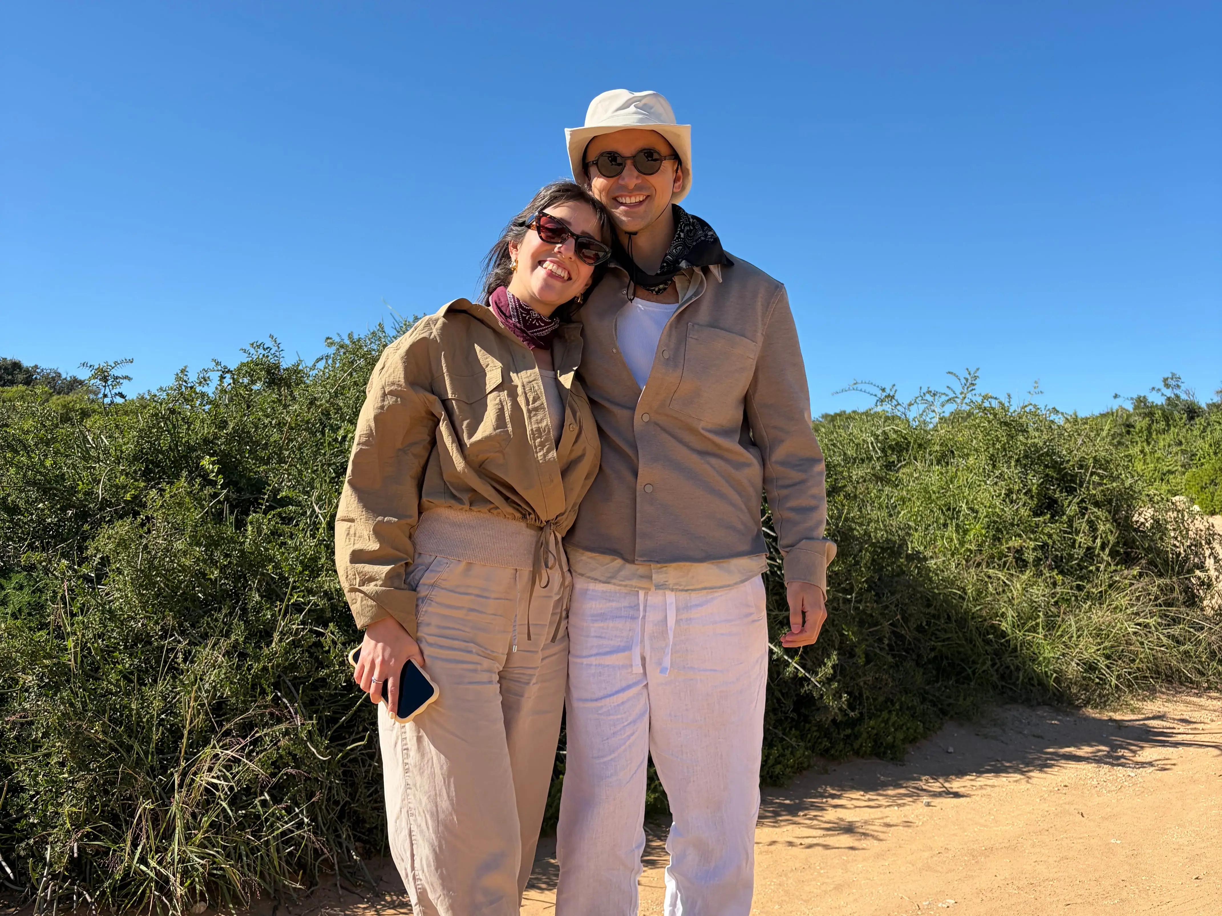 The writer and his partner standing in front of greenery on a beach.
