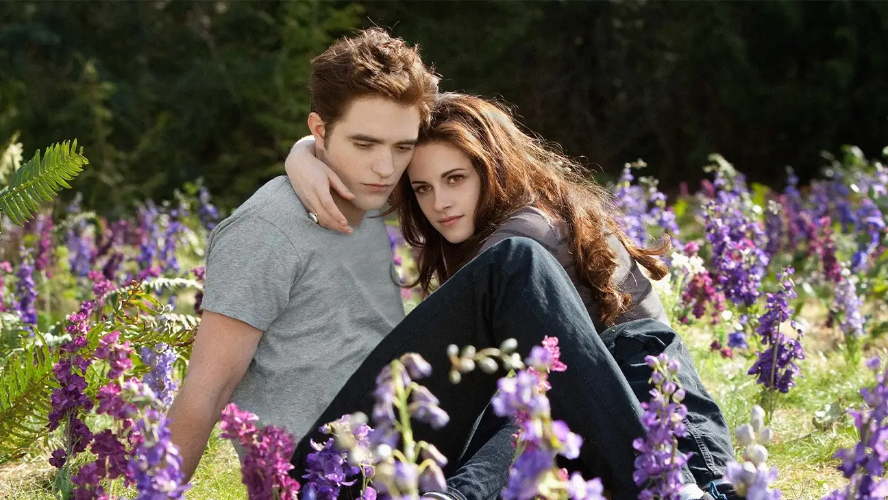 Robert Pattinson and Kristen Stewart with their arms around each other in a field in Twilight