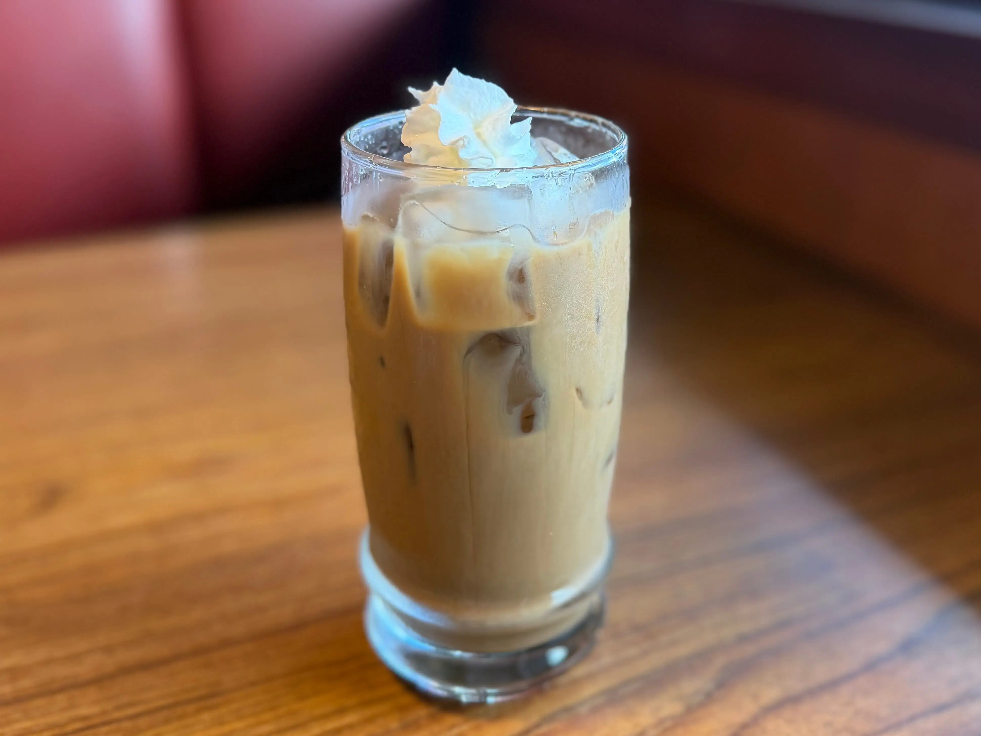 A small cold brew that's not completely filled to the top, with a dollop of whipped cream.
