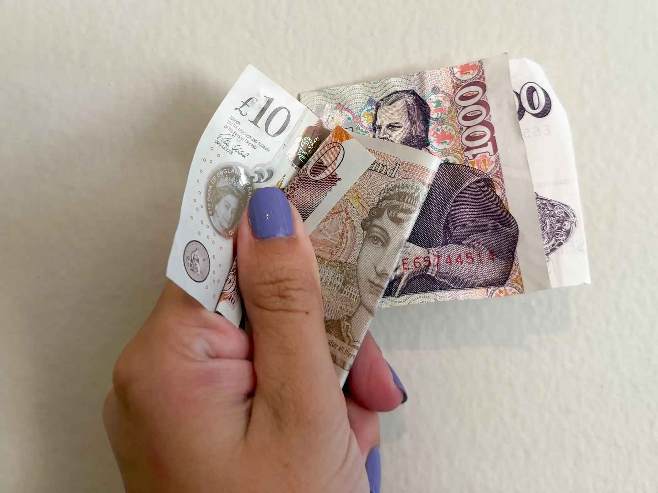 The writer is holding several pieces of foreign currency.