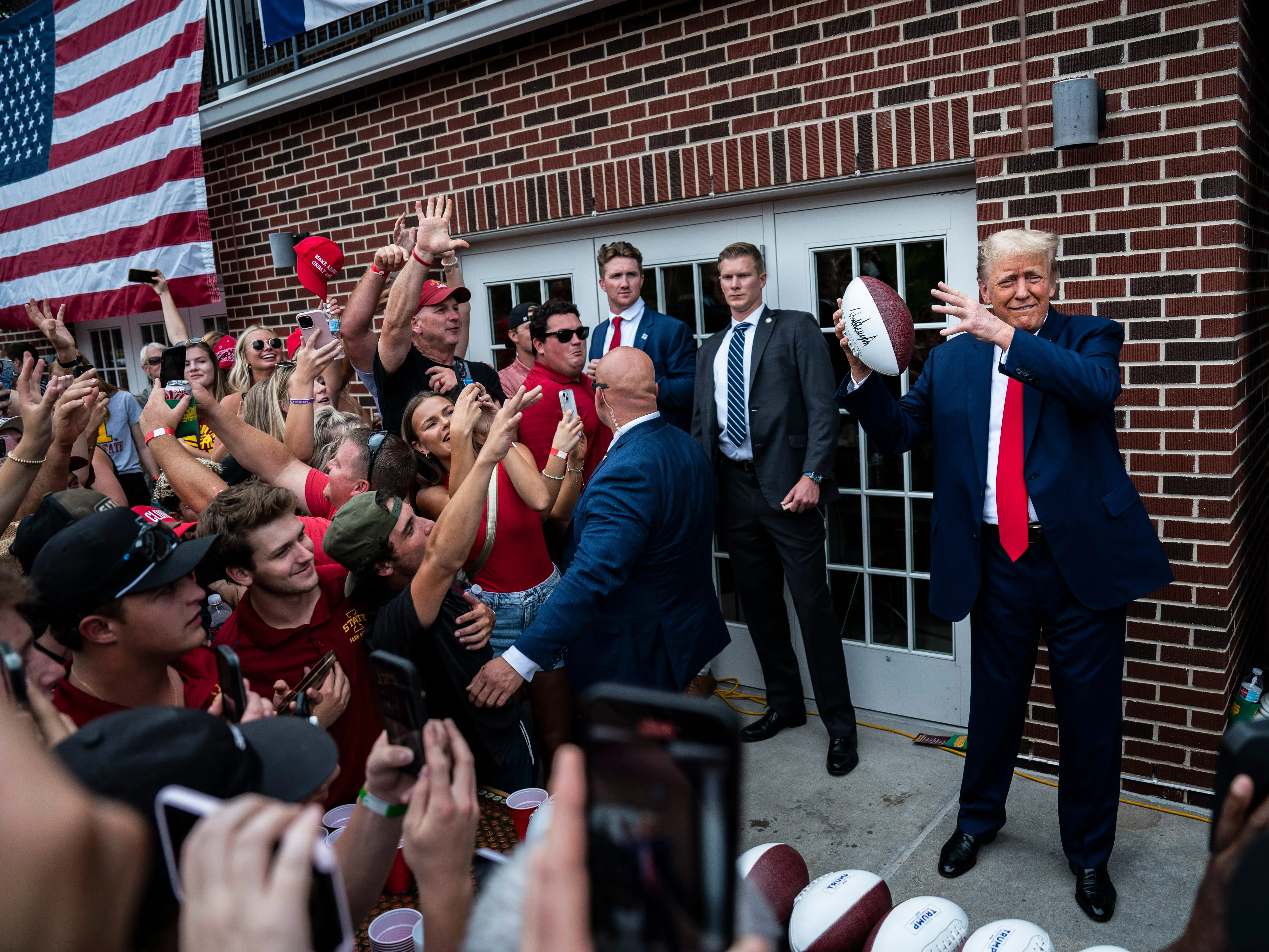 Former President Donald Trump throws a football into a crowd during a visit to the Alpha Gamma Rho fraternity before a NCAA college football game between Iowa State University and the University of Iowa at Jack Trice Stadium on Saturday, Sept 09, 2023, in Ames, Iowa.