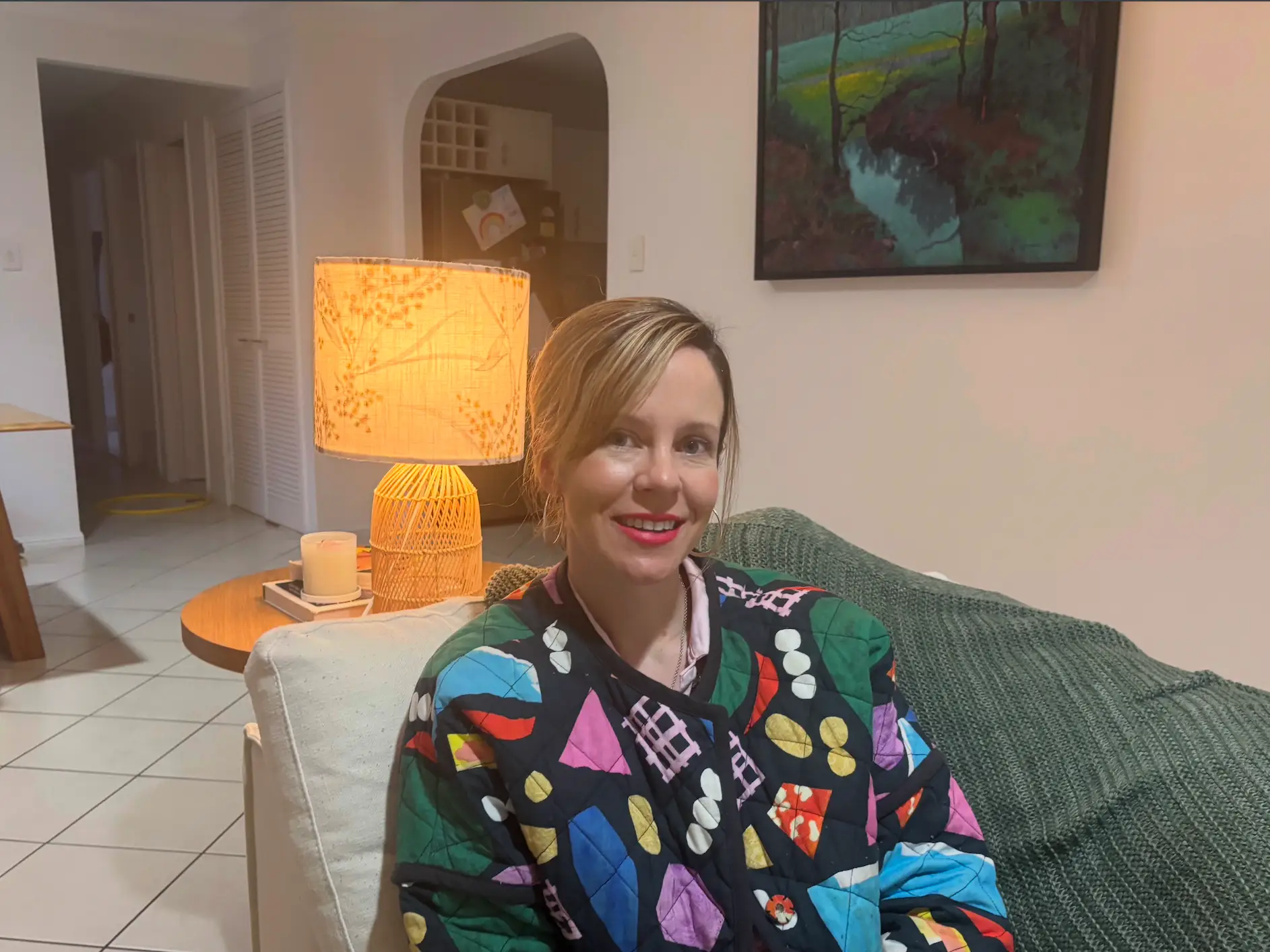 the author sitting on a couch with a lamp behind her, she is wearing a colorful jacket The author's family of five moved into a three-bedroom duplex.