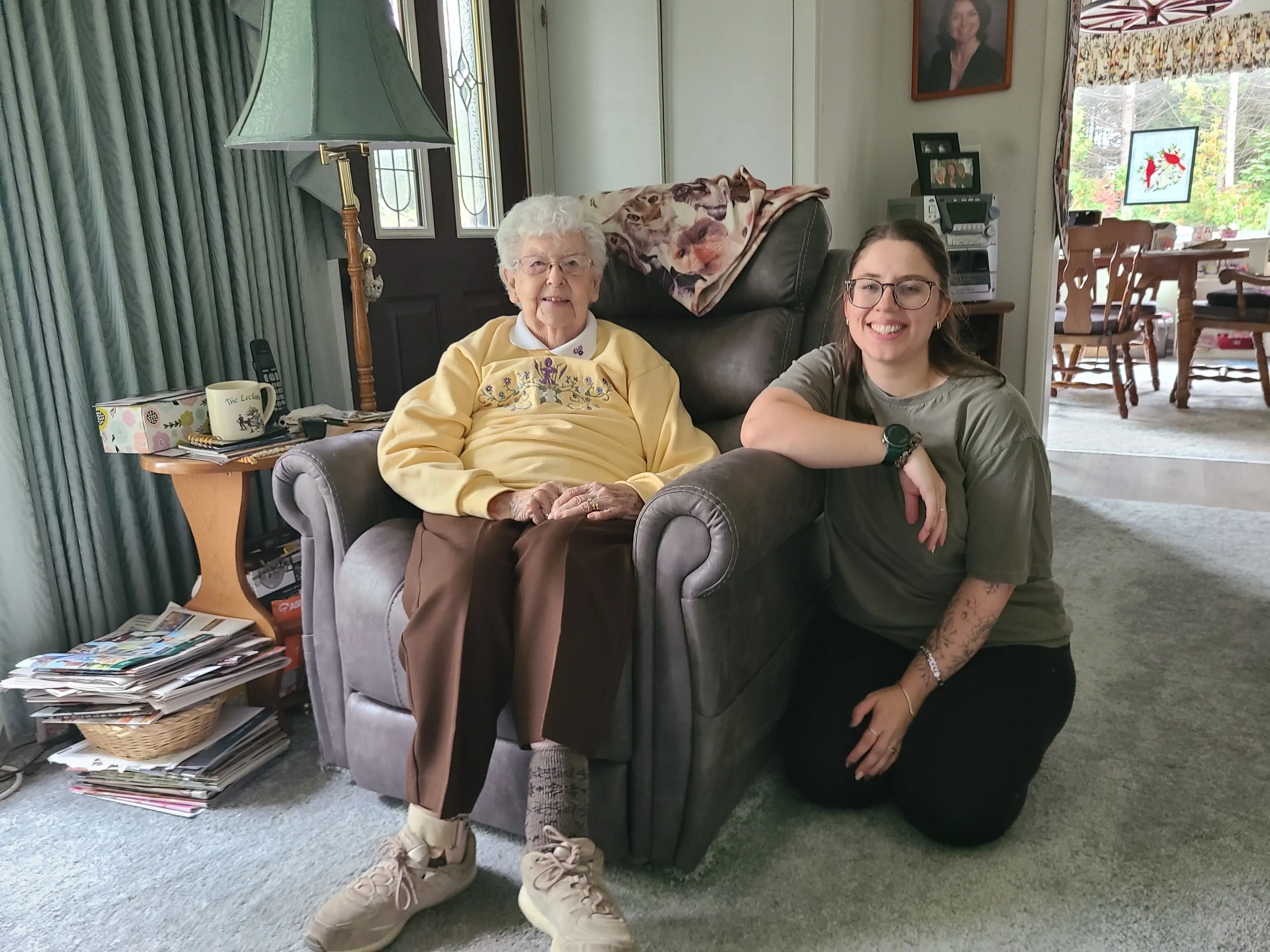 Woman kneeling, smiling with older woman in chair