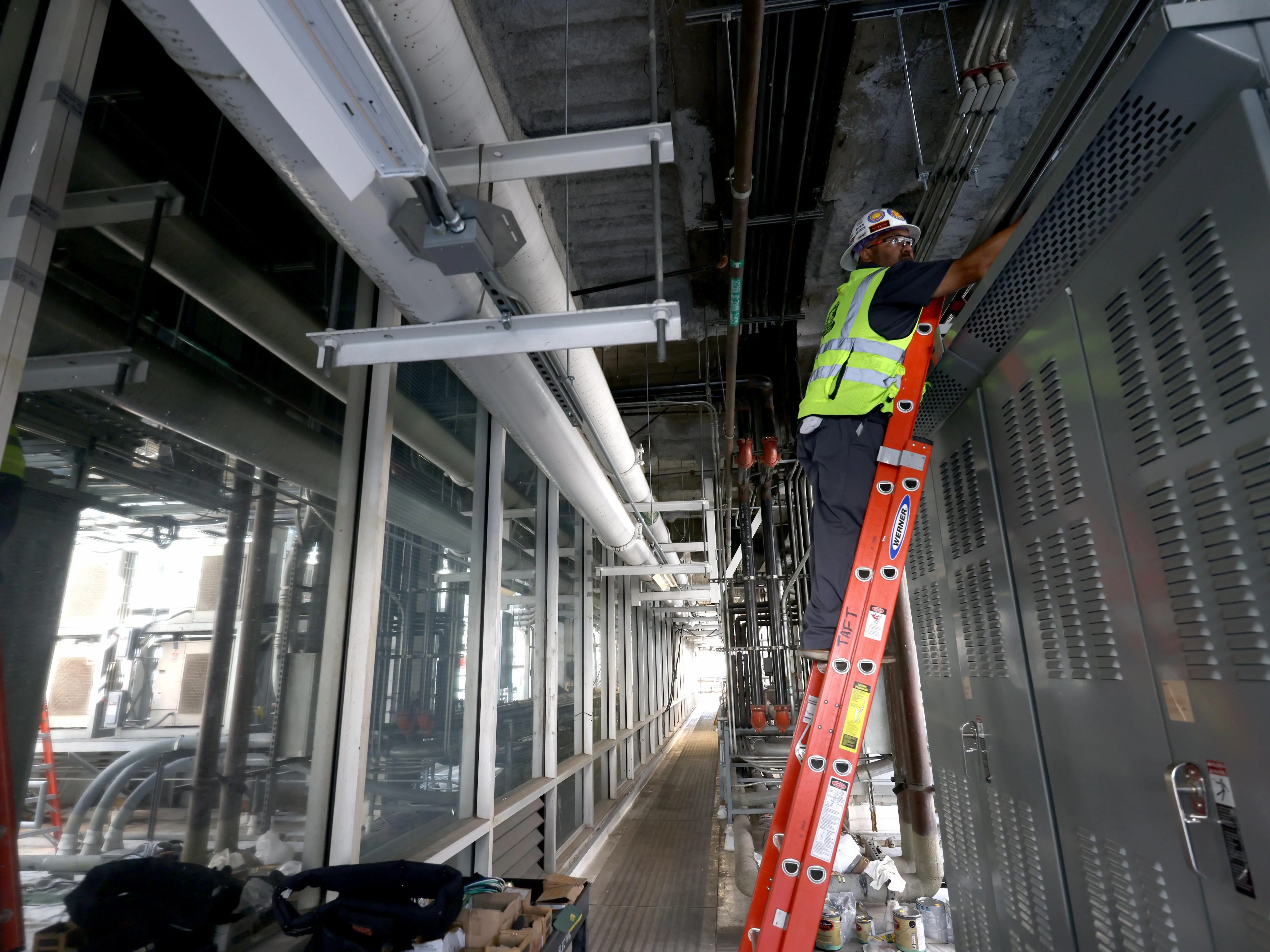A worker wearing a hard hat on a ladder