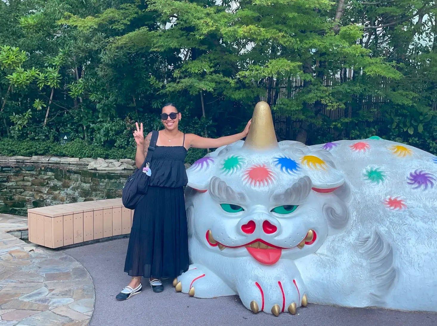 The writer holding up a peace sign while standing next to a white animal statue in Japan.