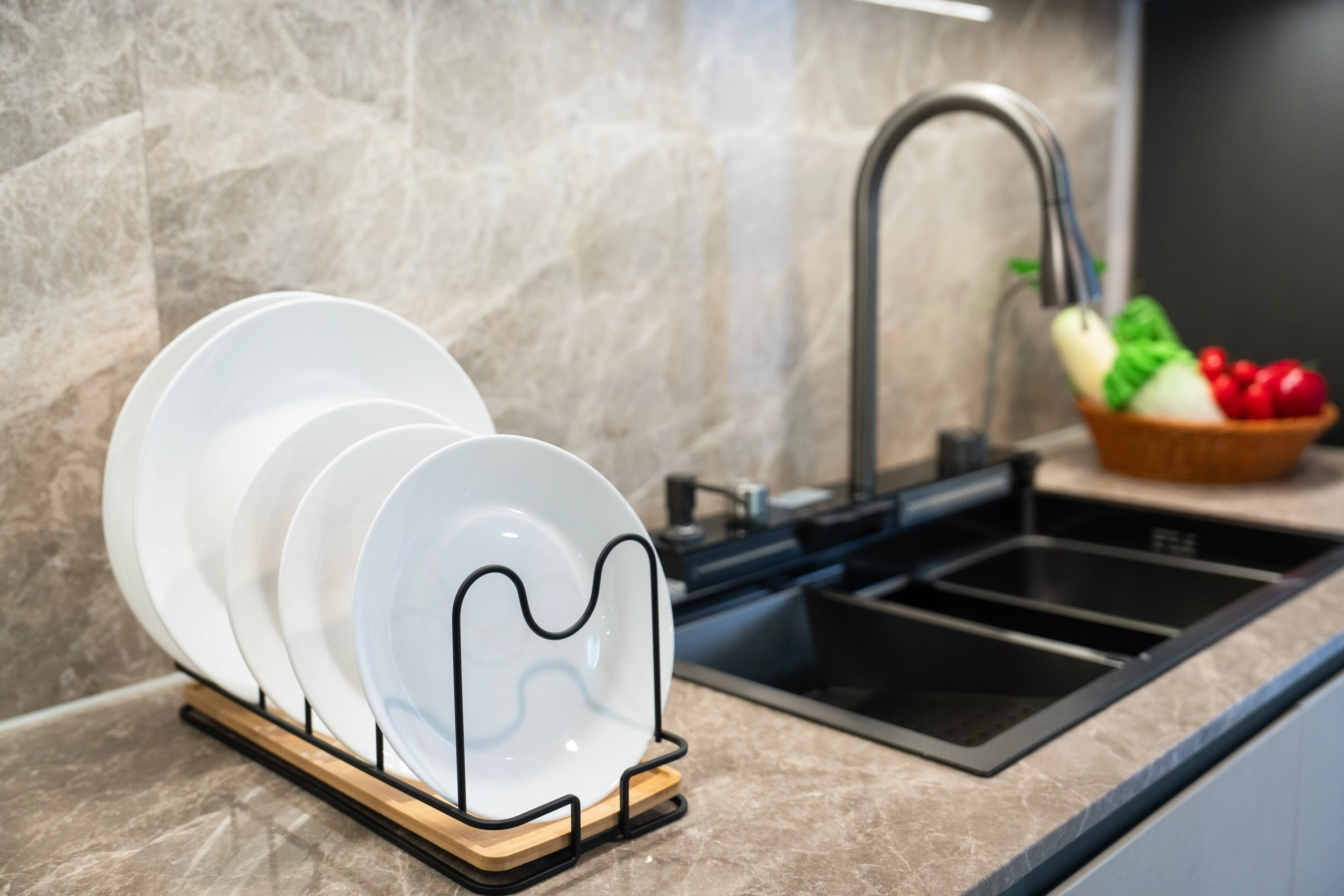 Kitchen with dishrack, black faucet, stone countertops and backdrop