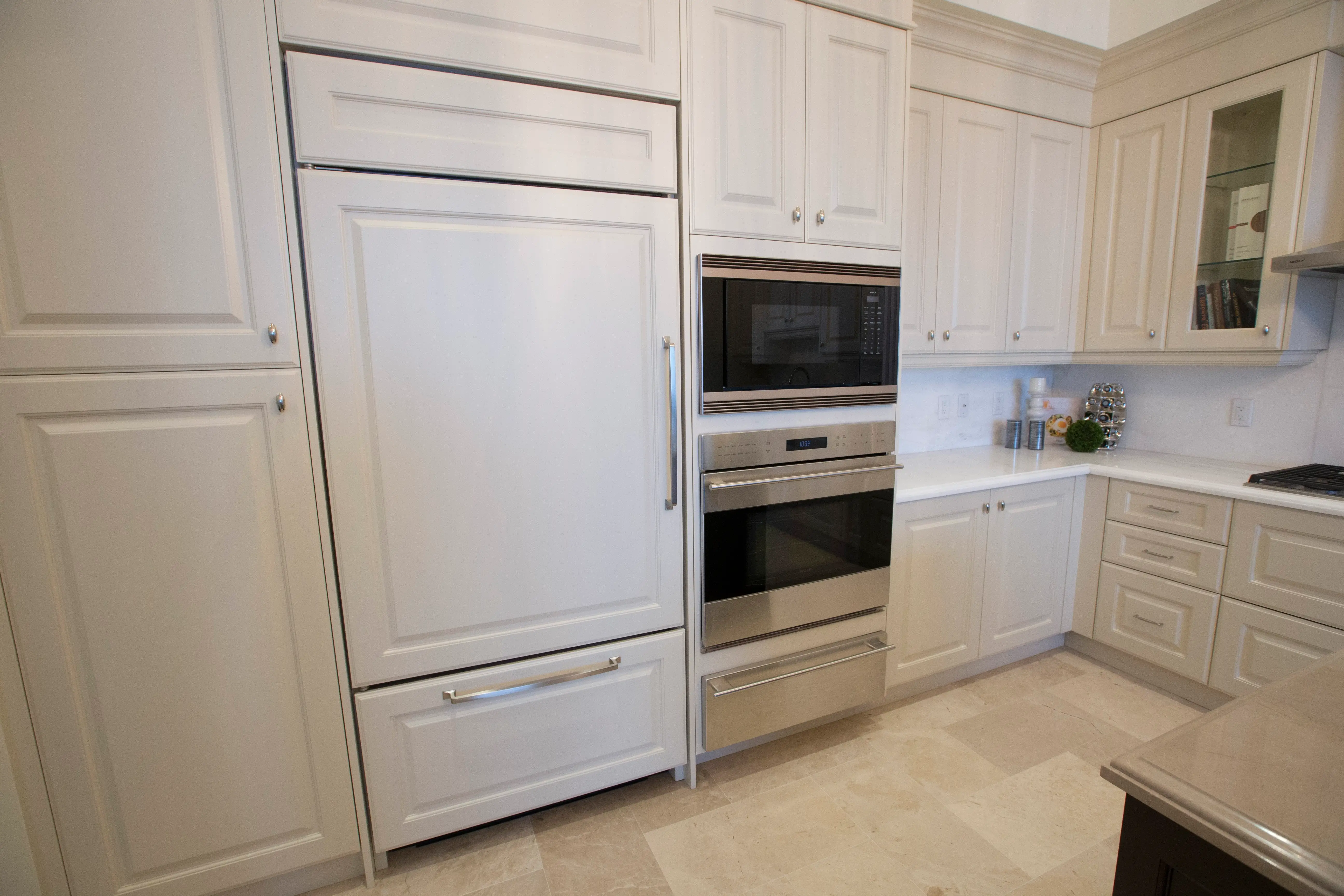 White cabinets in kitchen with fridge hidden behind cabinet doors