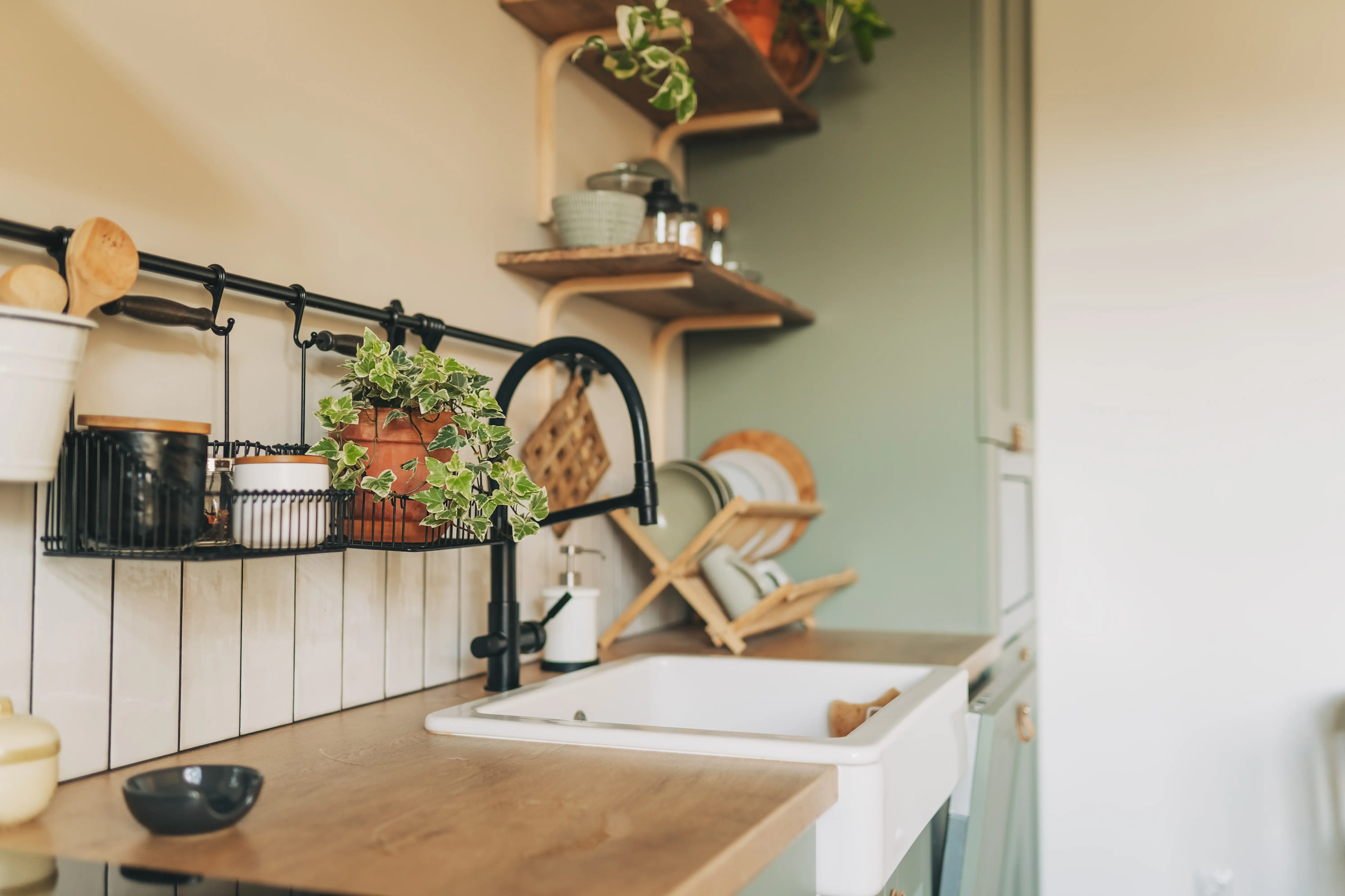 Kitchen interior with light green cabinets, large rustic white porcelain sink and