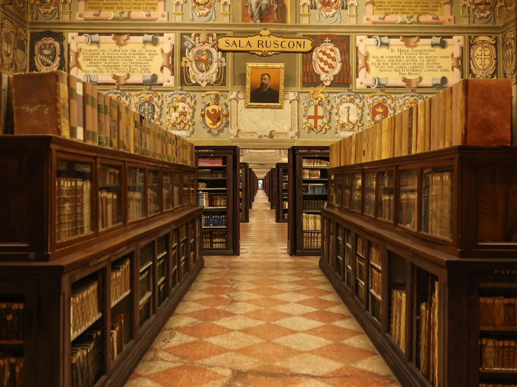 The Archiginnasio Municipal Library is filled with wooden bookcases, old volumes, painted walls, and portraits.
