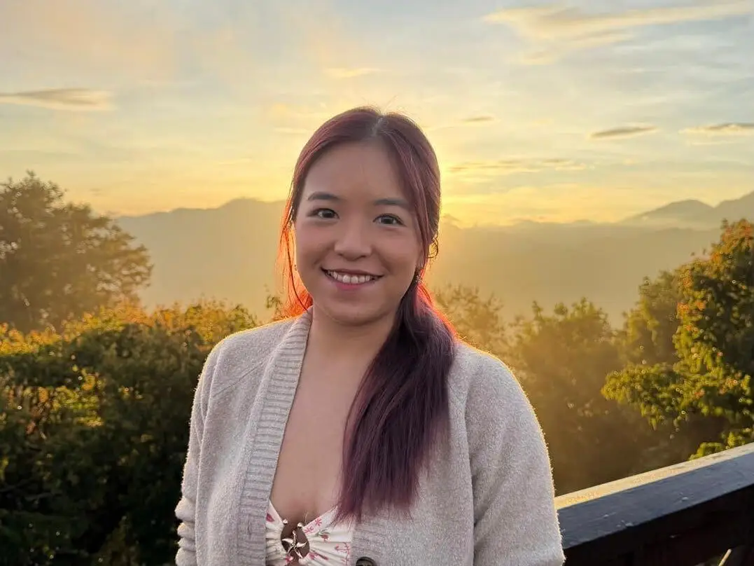 A woman taking a photo during a sunset.