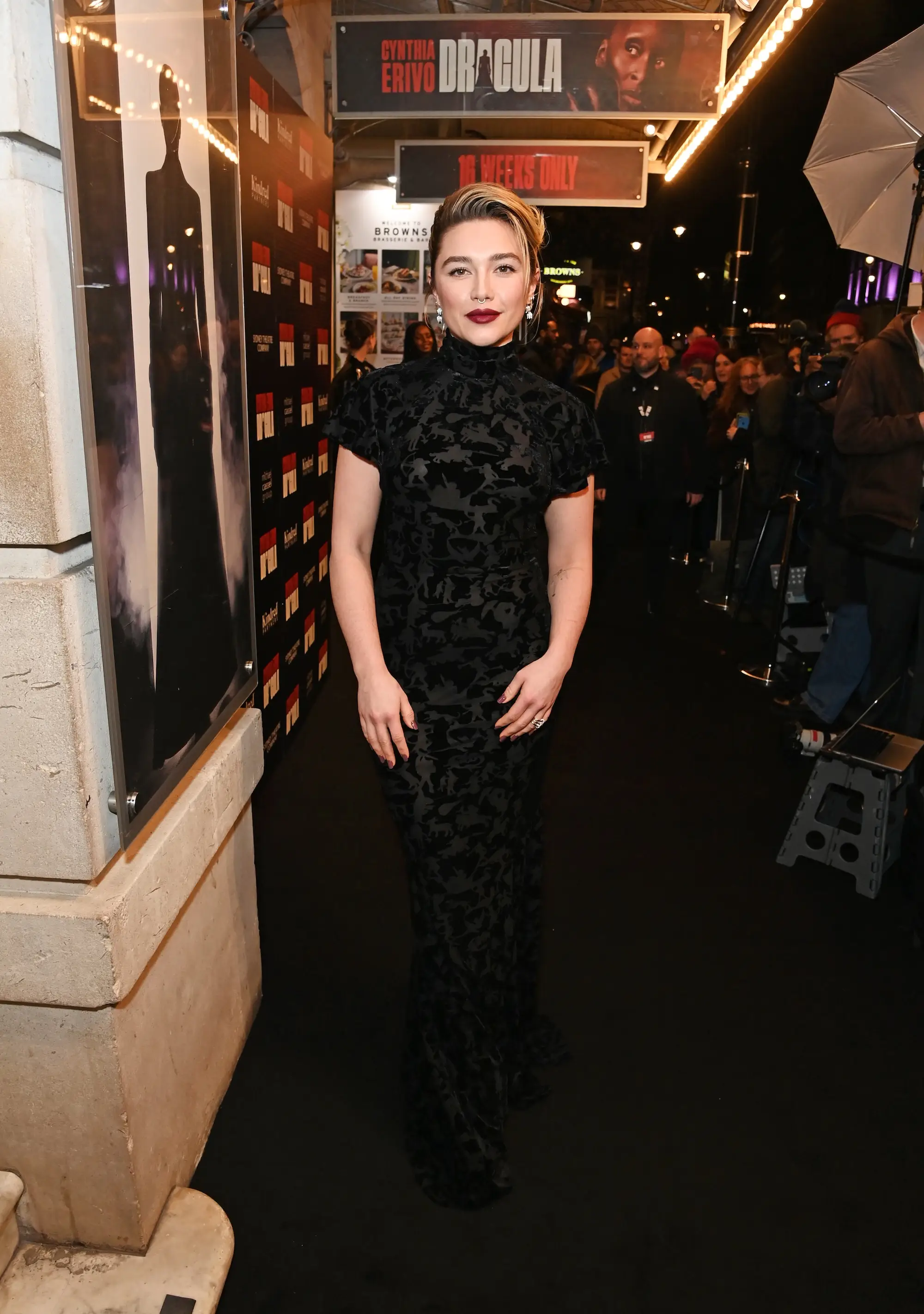 Florence Pugh poses on a nighttime arrivals carpet beneath a Cynthia Erivo