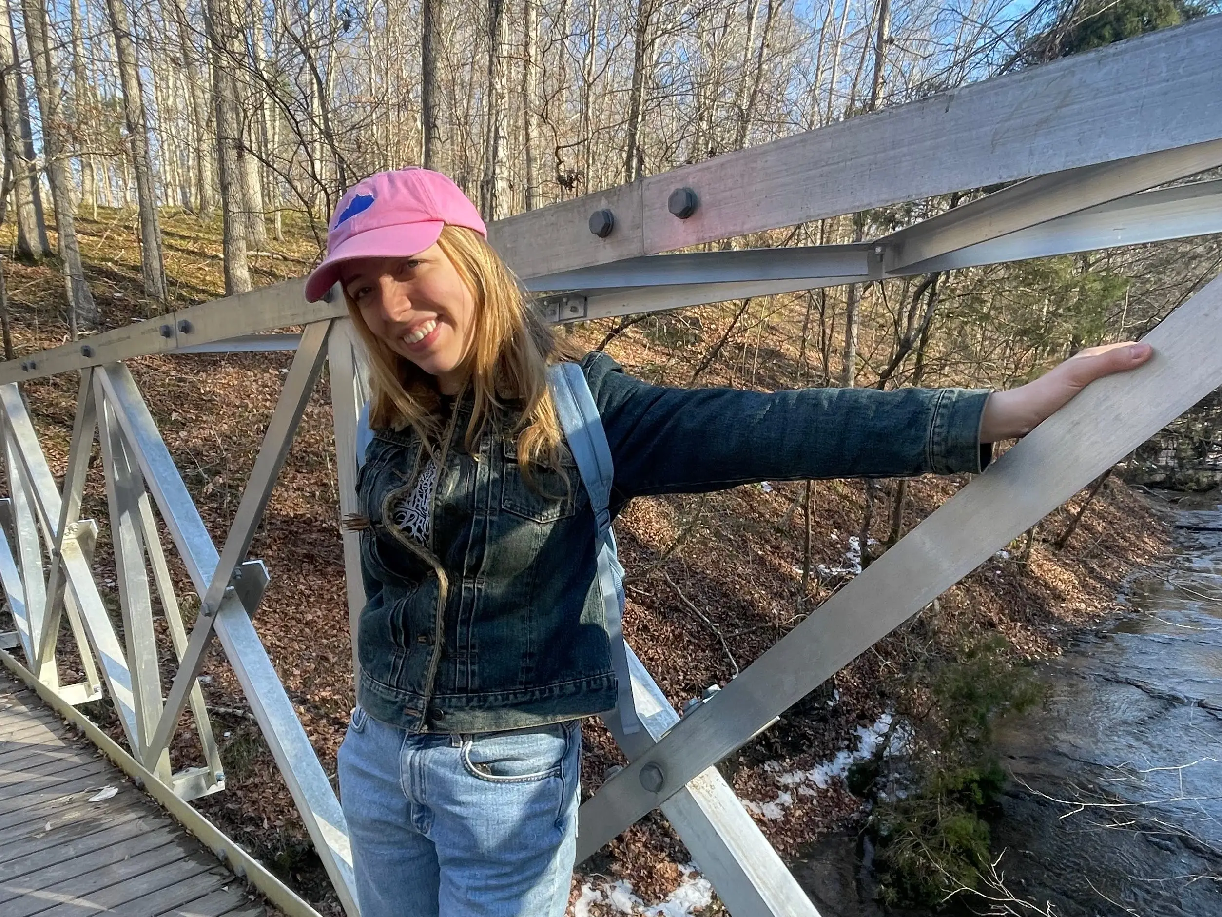 theauthor standing on a bridge wearing a pink hat and smiling