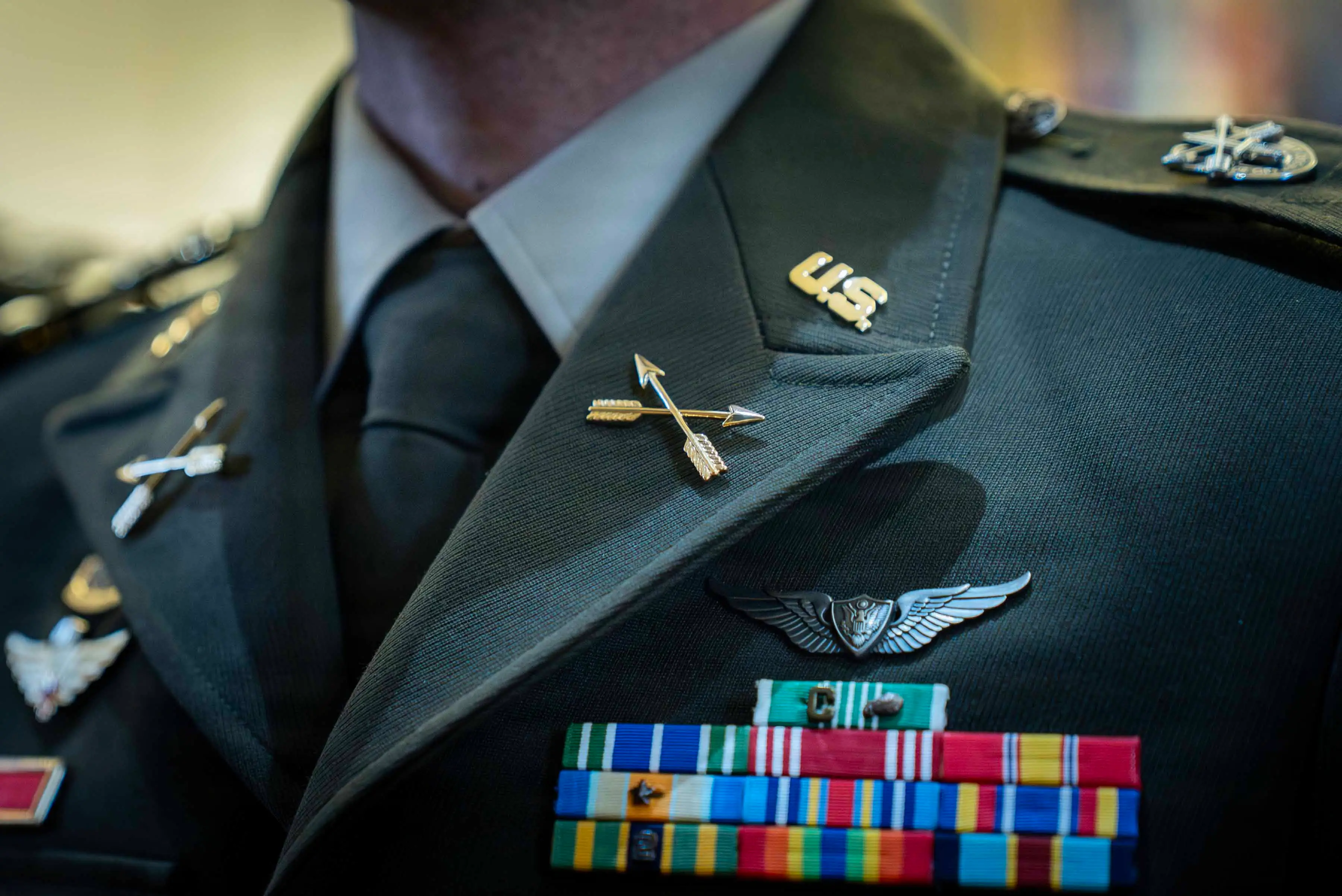 A close-up of pins on a dark green jacket worn by a man.