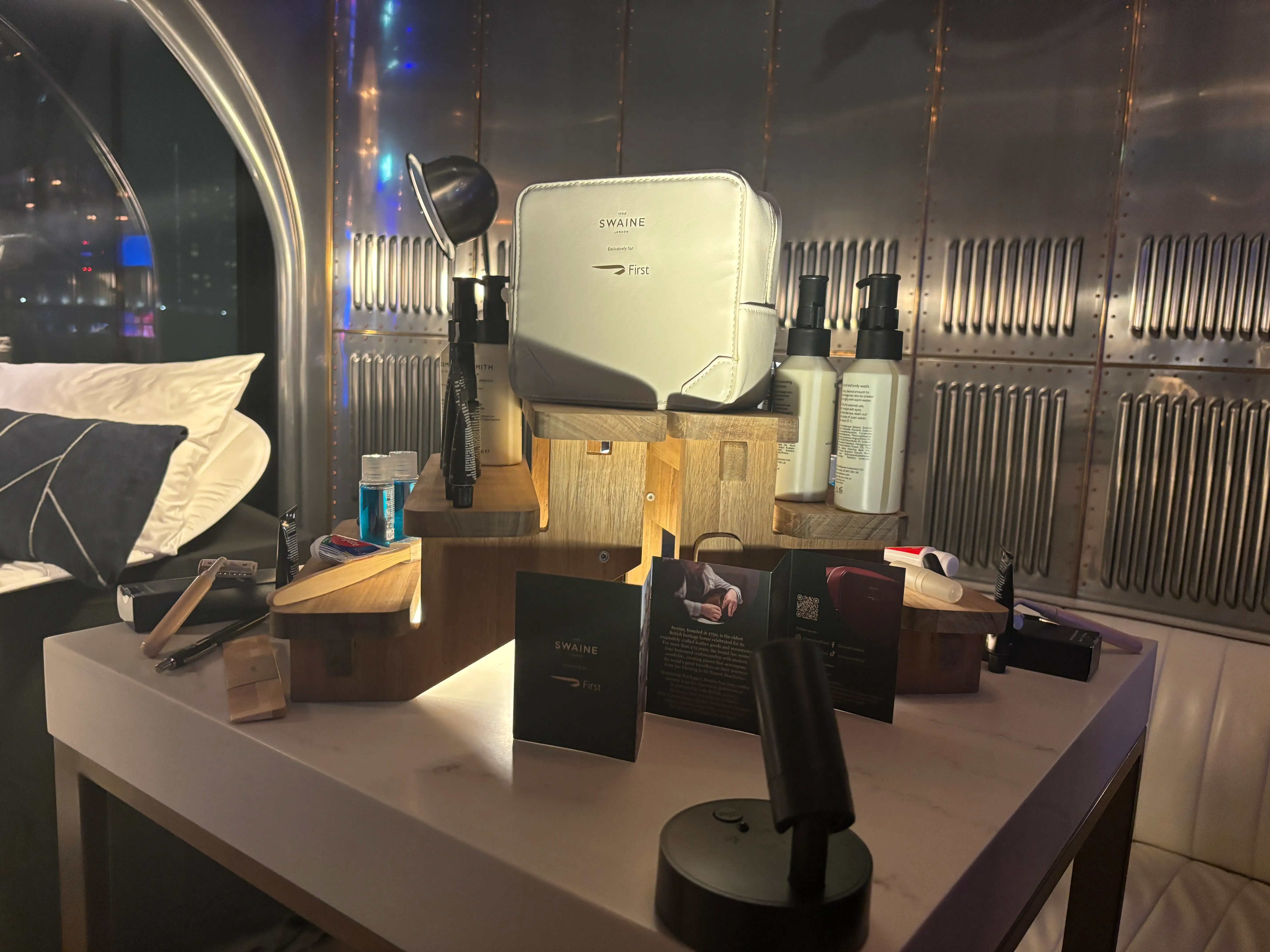 A British Airways first-class amenity kit in white, made by Swaine, with the products laid out at a media event.