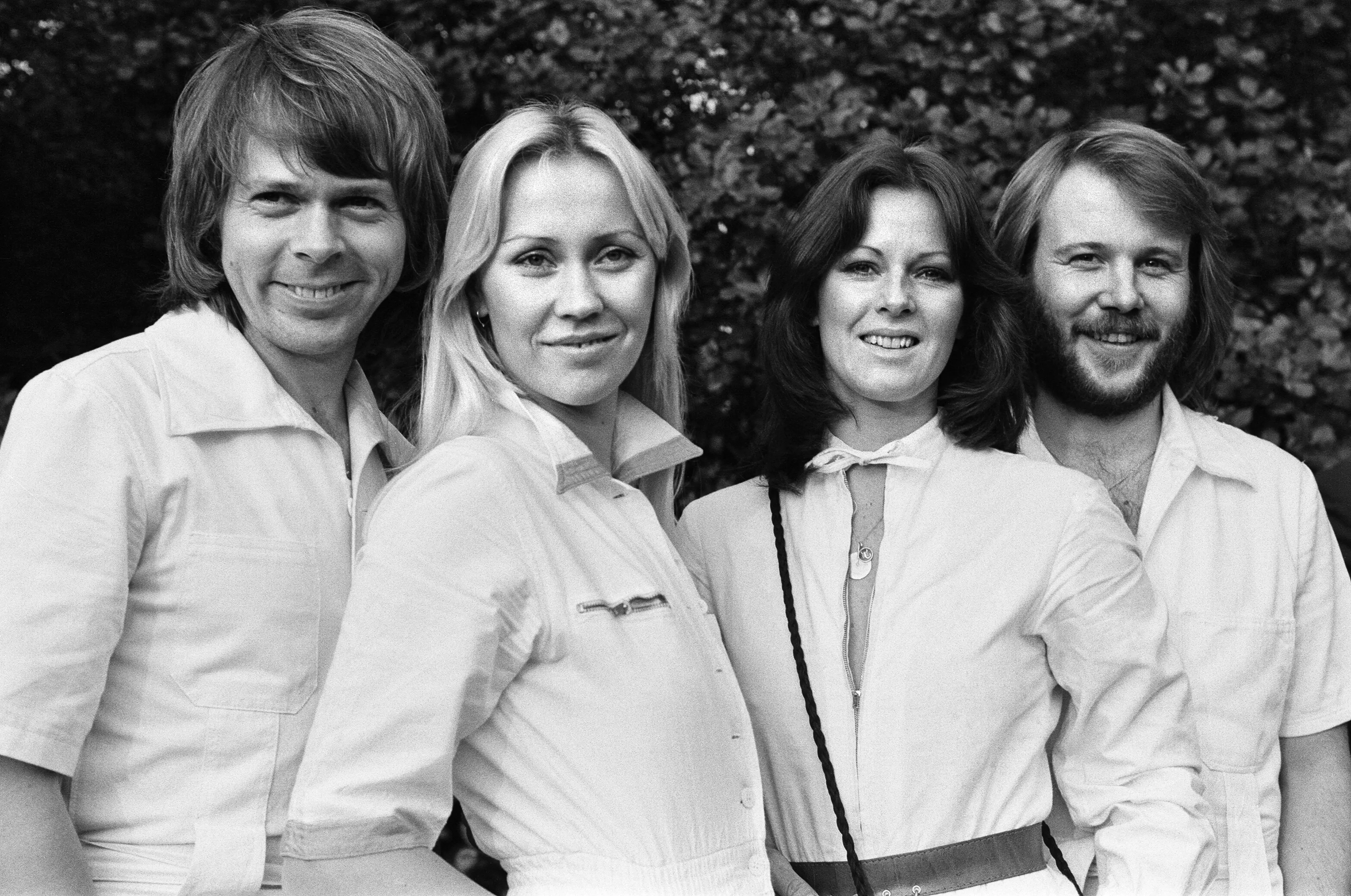 ABBA members pose in front of trees.