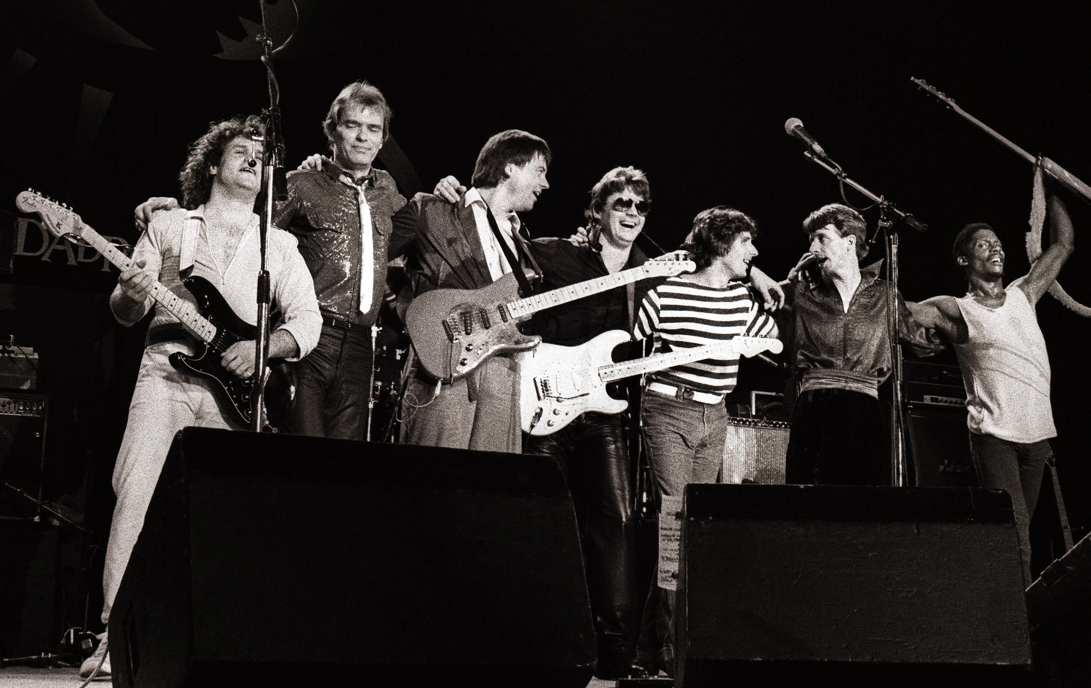 Seven members of The Steve Miller Band line up on a concert stage.