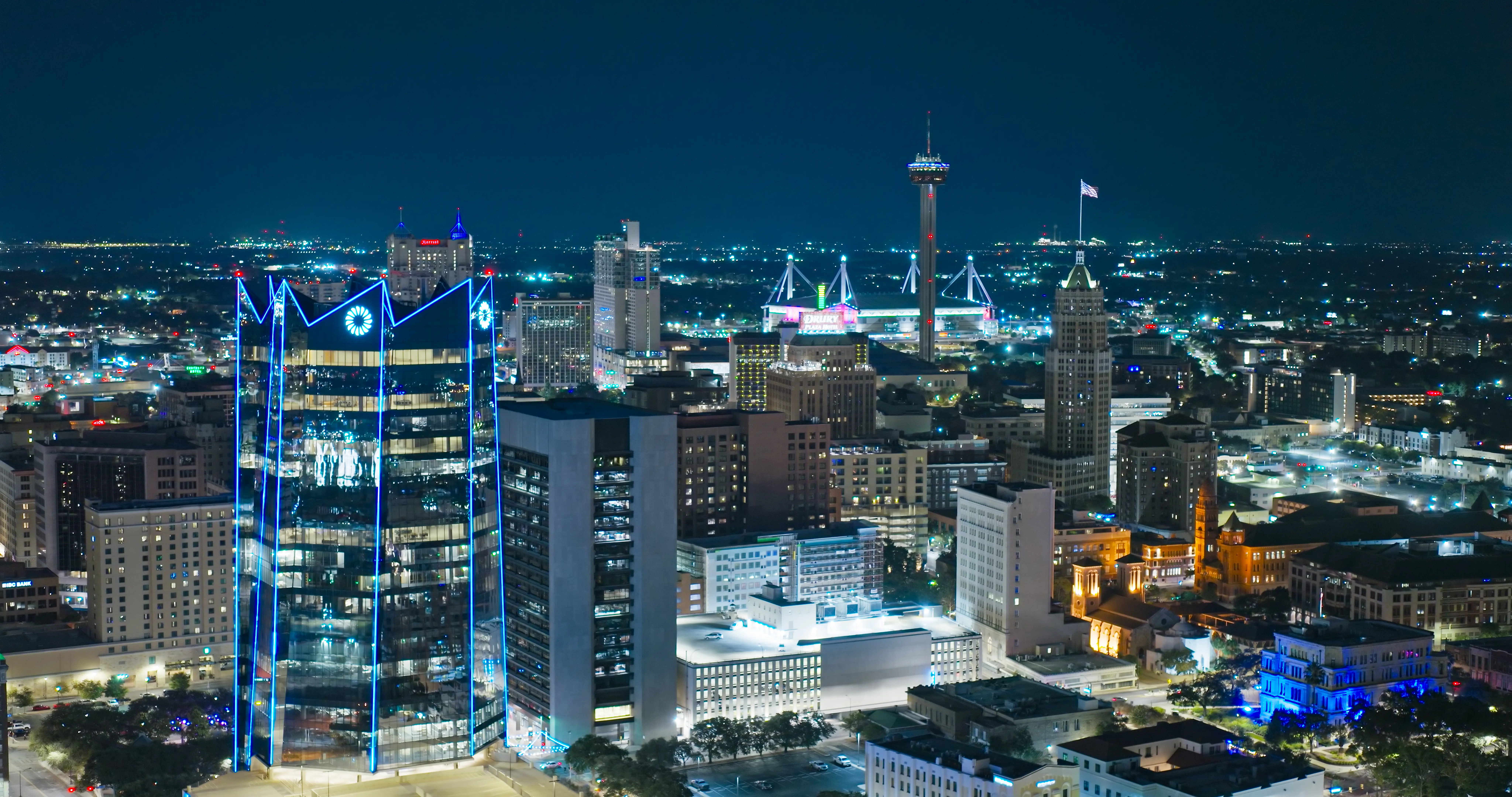 Downtown San Antonio skyline glows at night with Tower of the Americas and illuminated high-rise buildings.