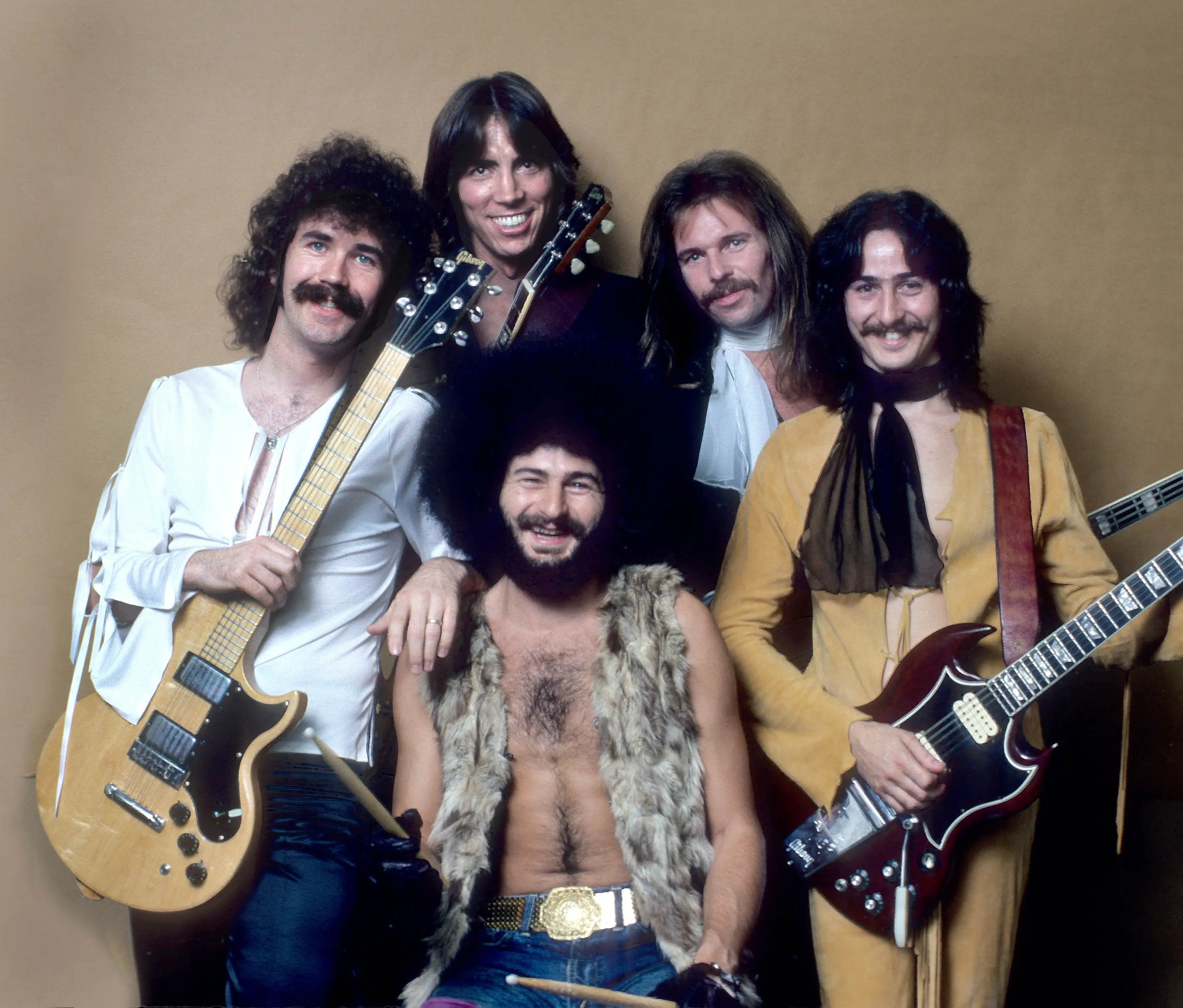 The band Boston poses and smiles with guitars.