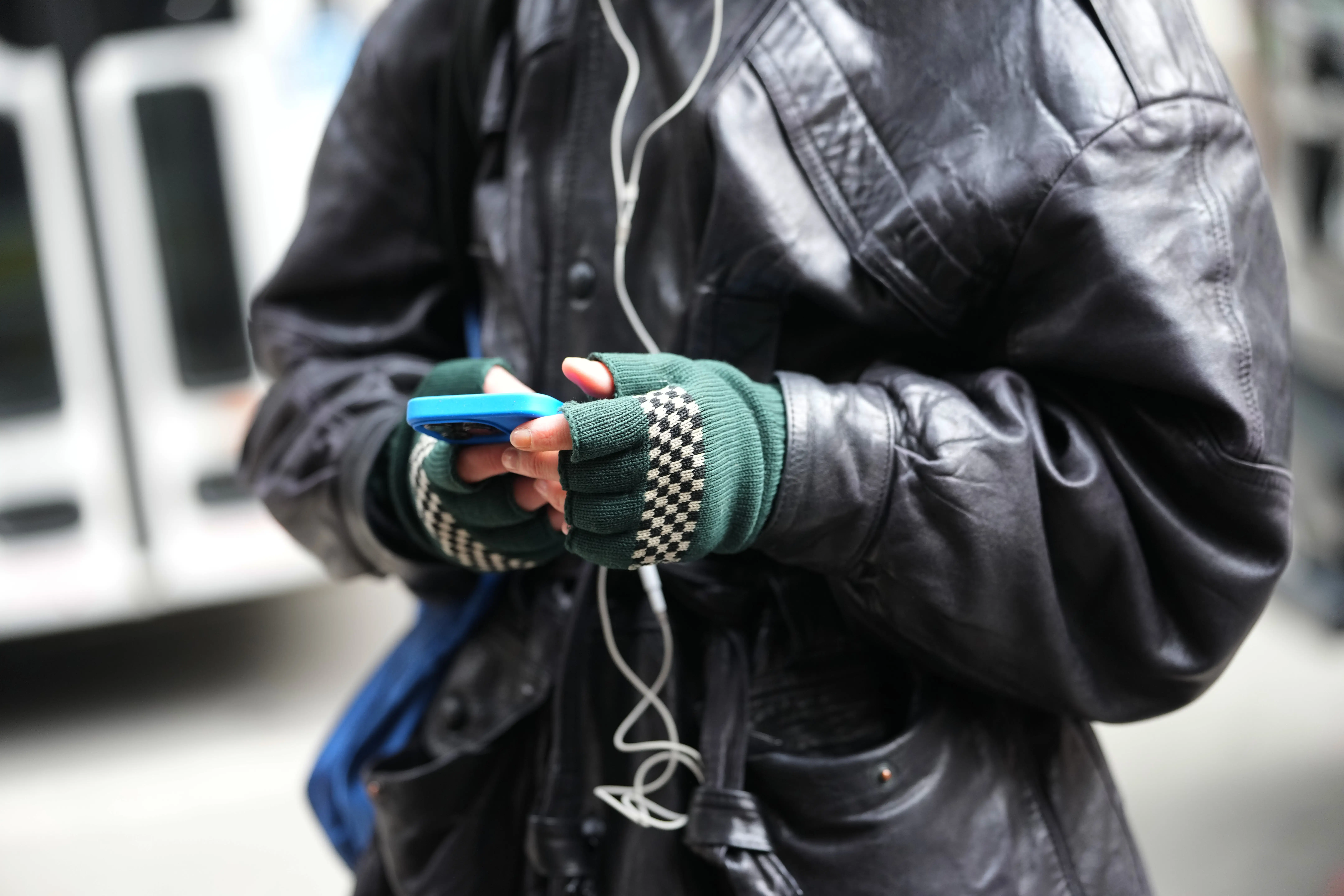A person listens to audio on their phone via headphones.