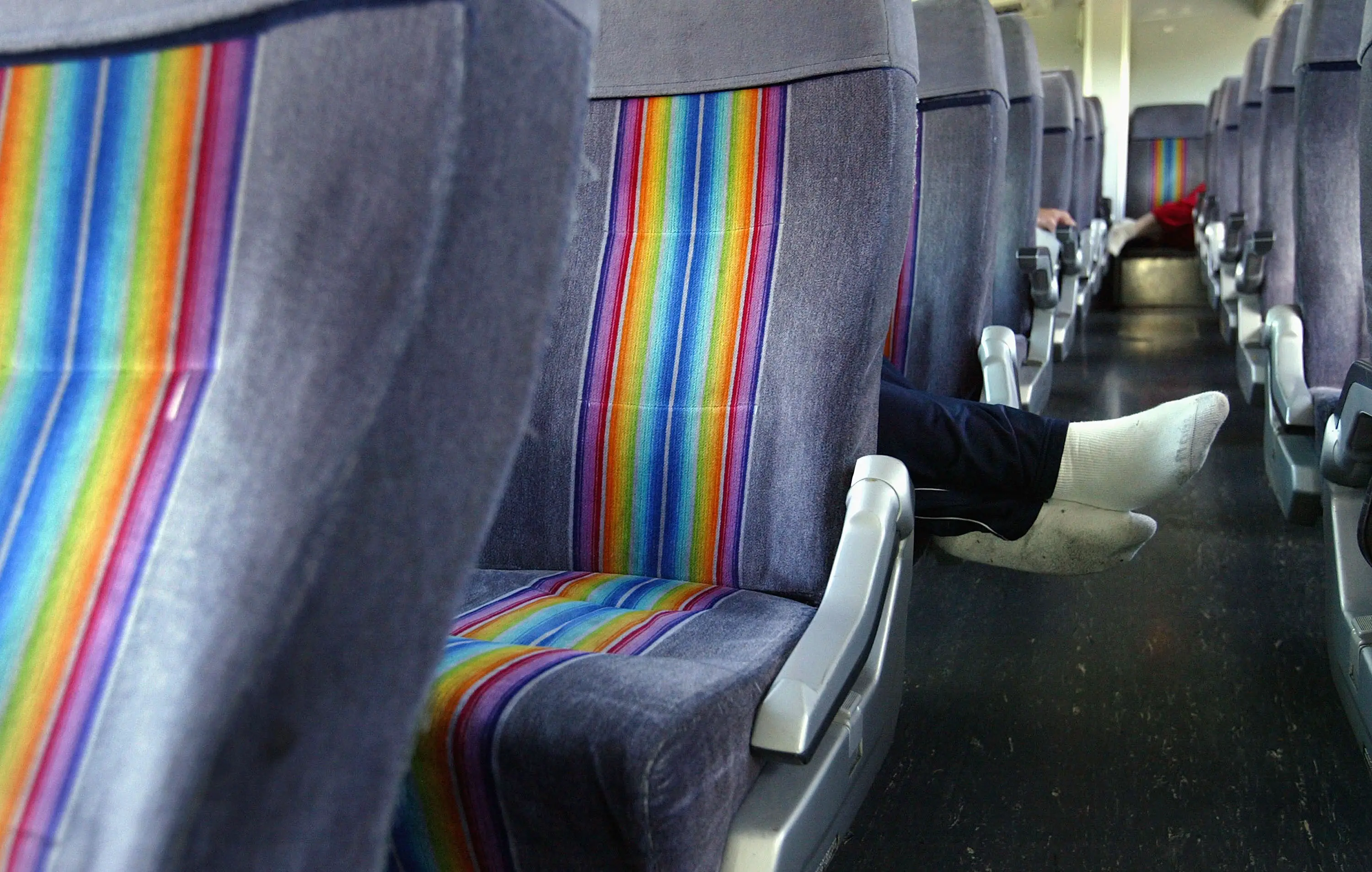 A person's feet stick out from a pair of seats on a Greyhound bus.