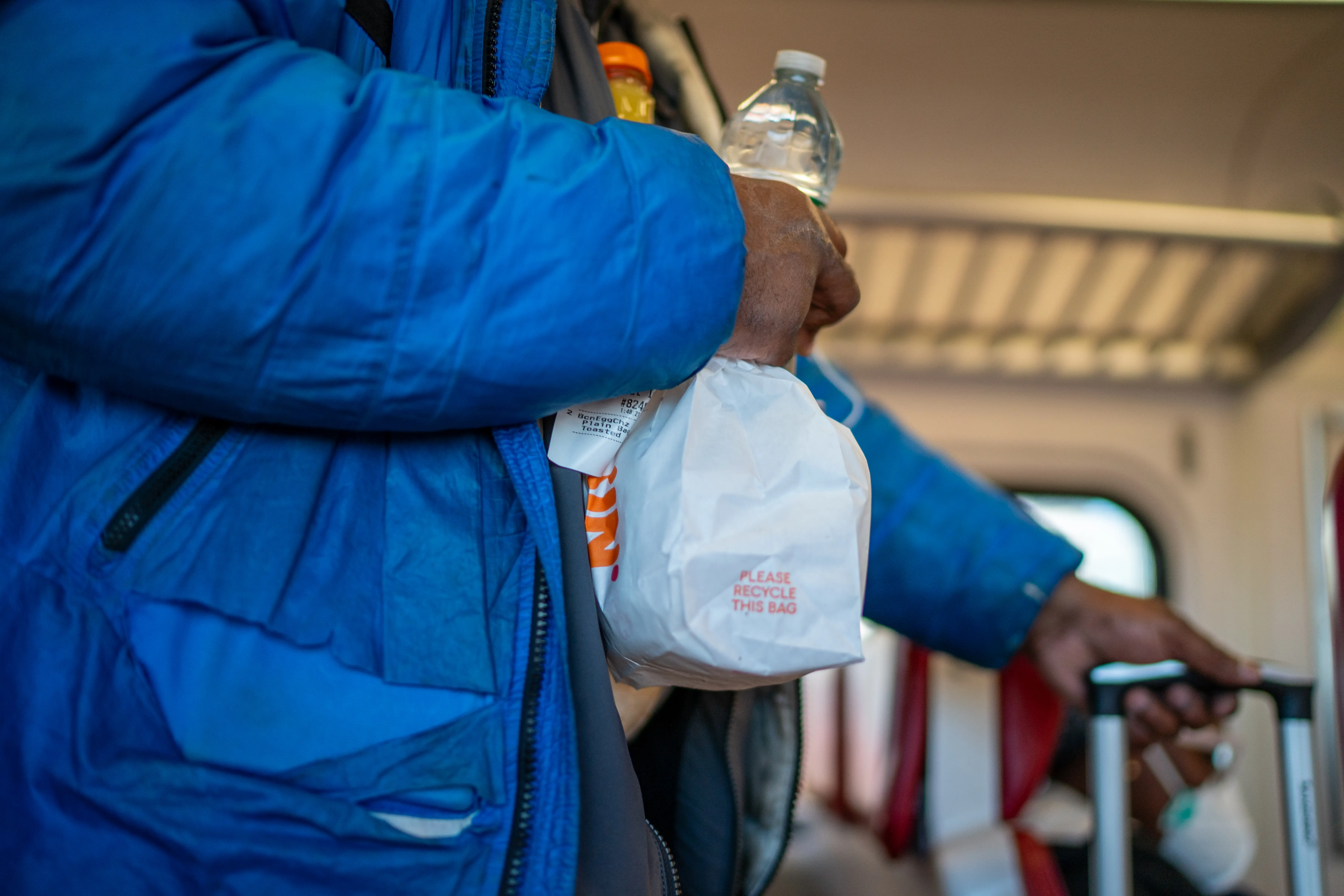 A person holds a bag of fast food on a Metro-North train.