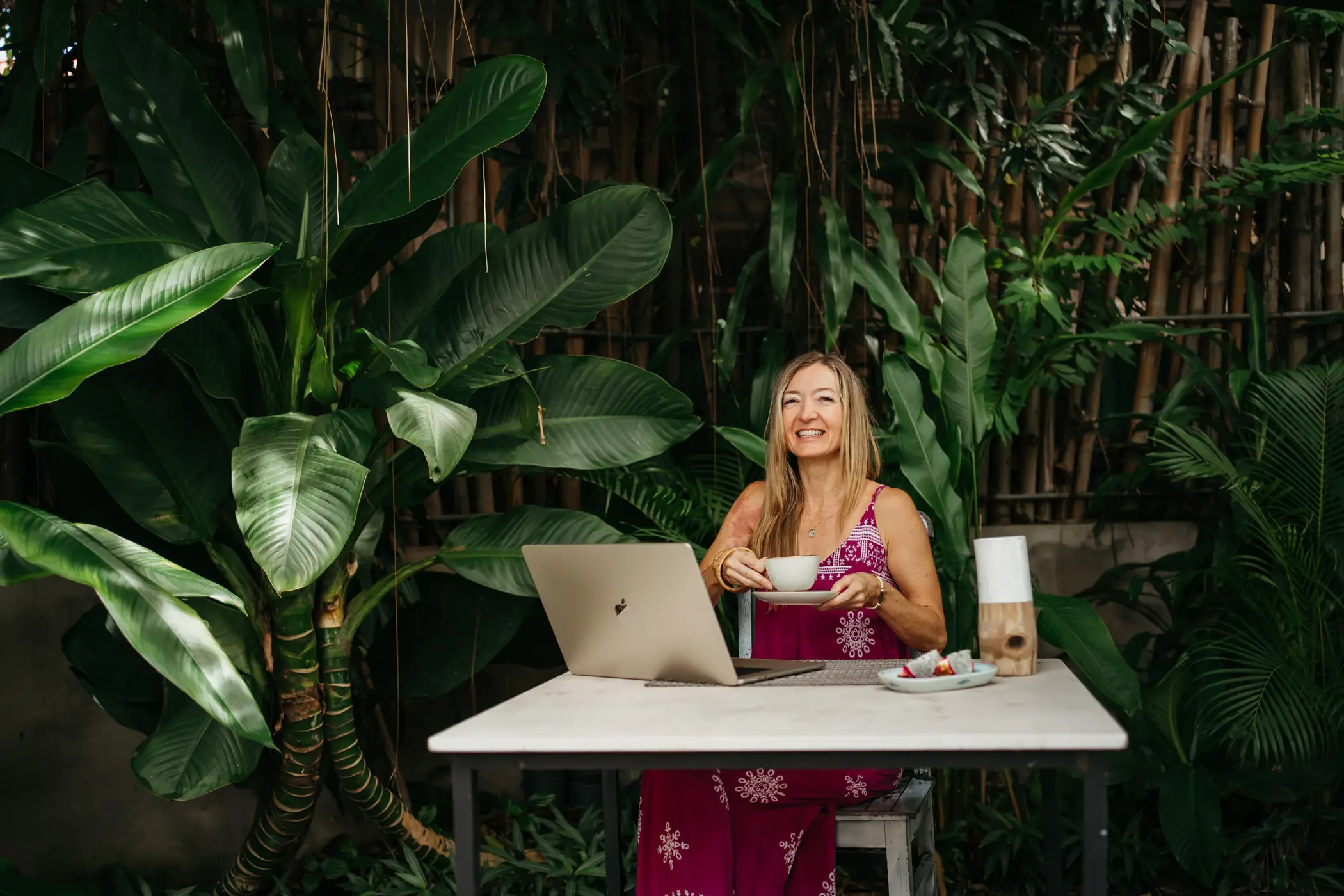 A woman holding a cup of tea and working on a laptop in Cambodia.