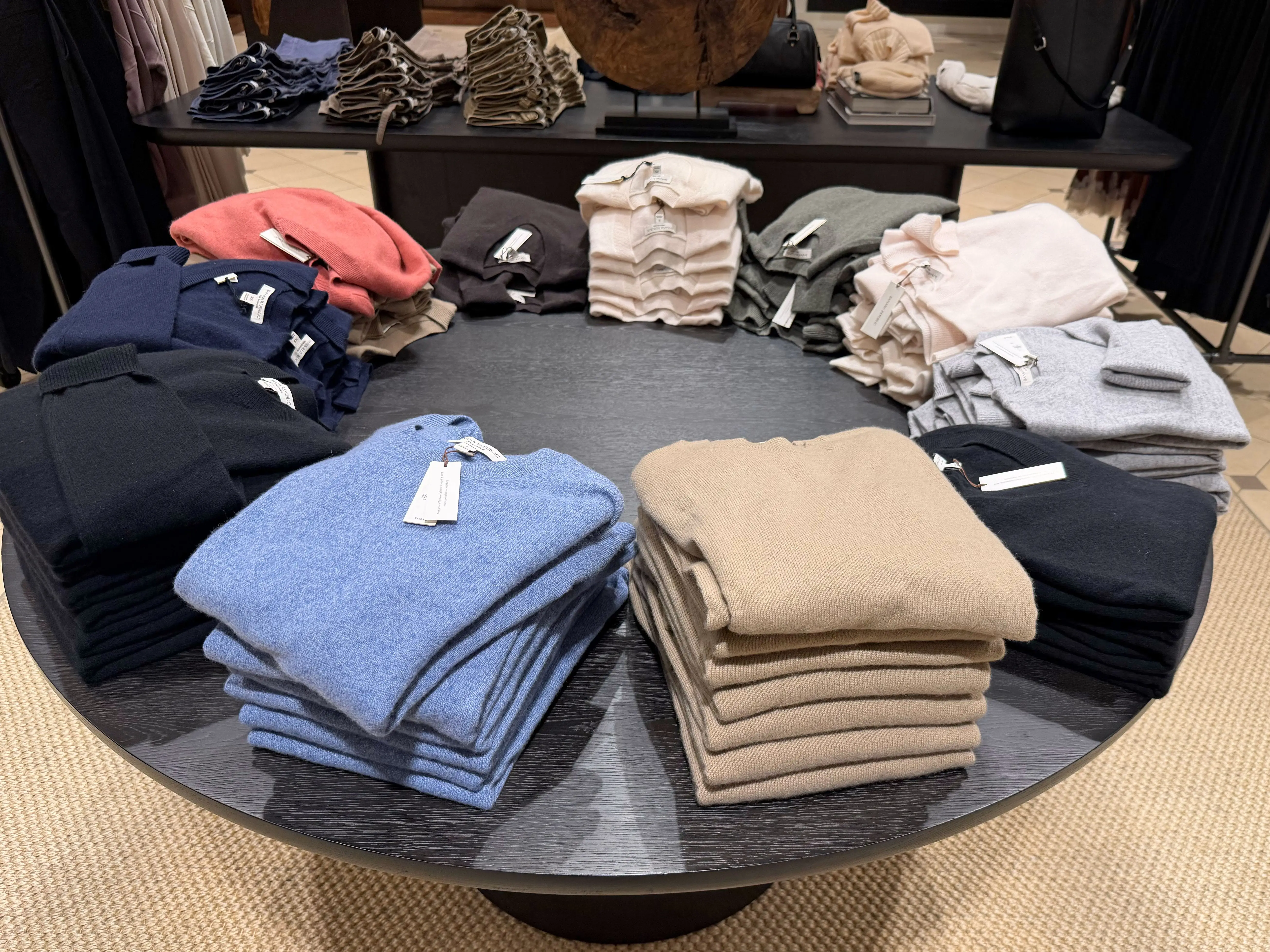A circular table lined with different colored sweaters.
