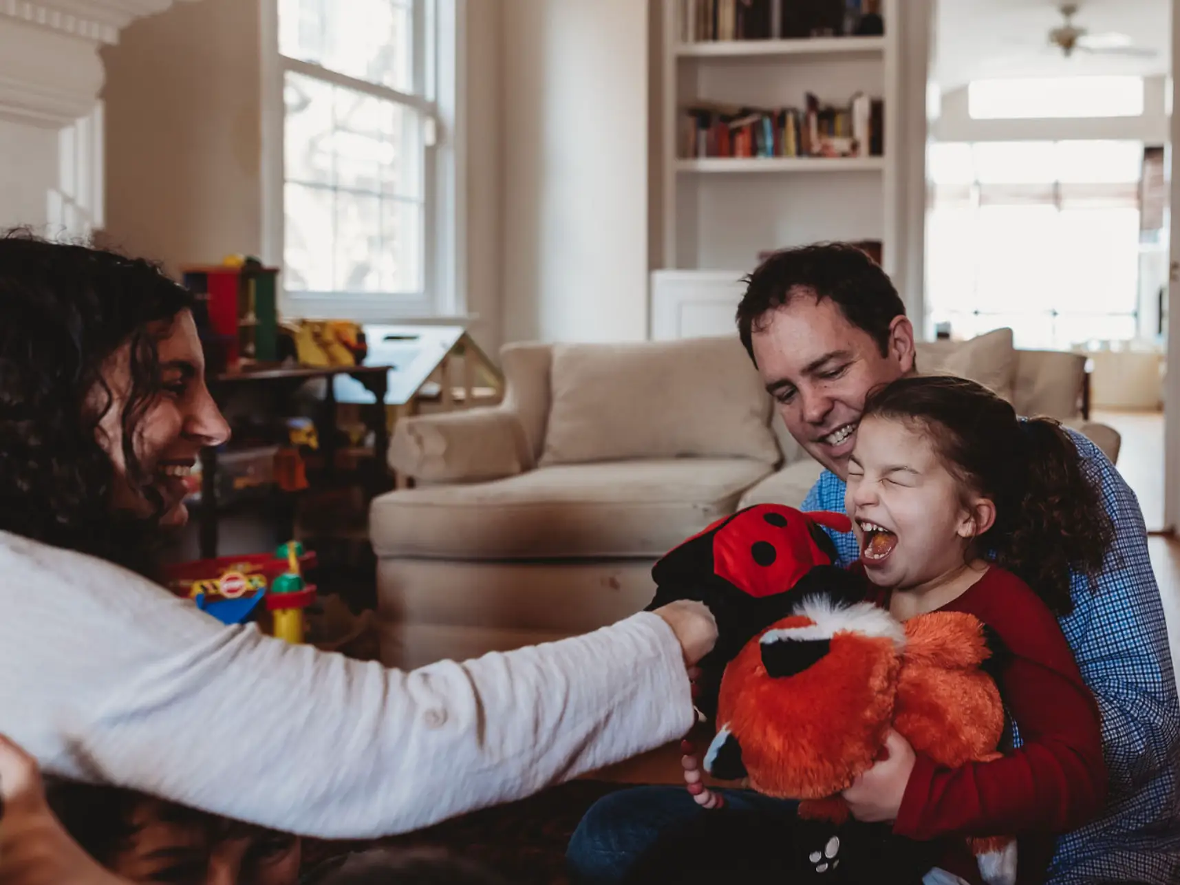 the author and her husband sitting on the floor and playing with their daughter