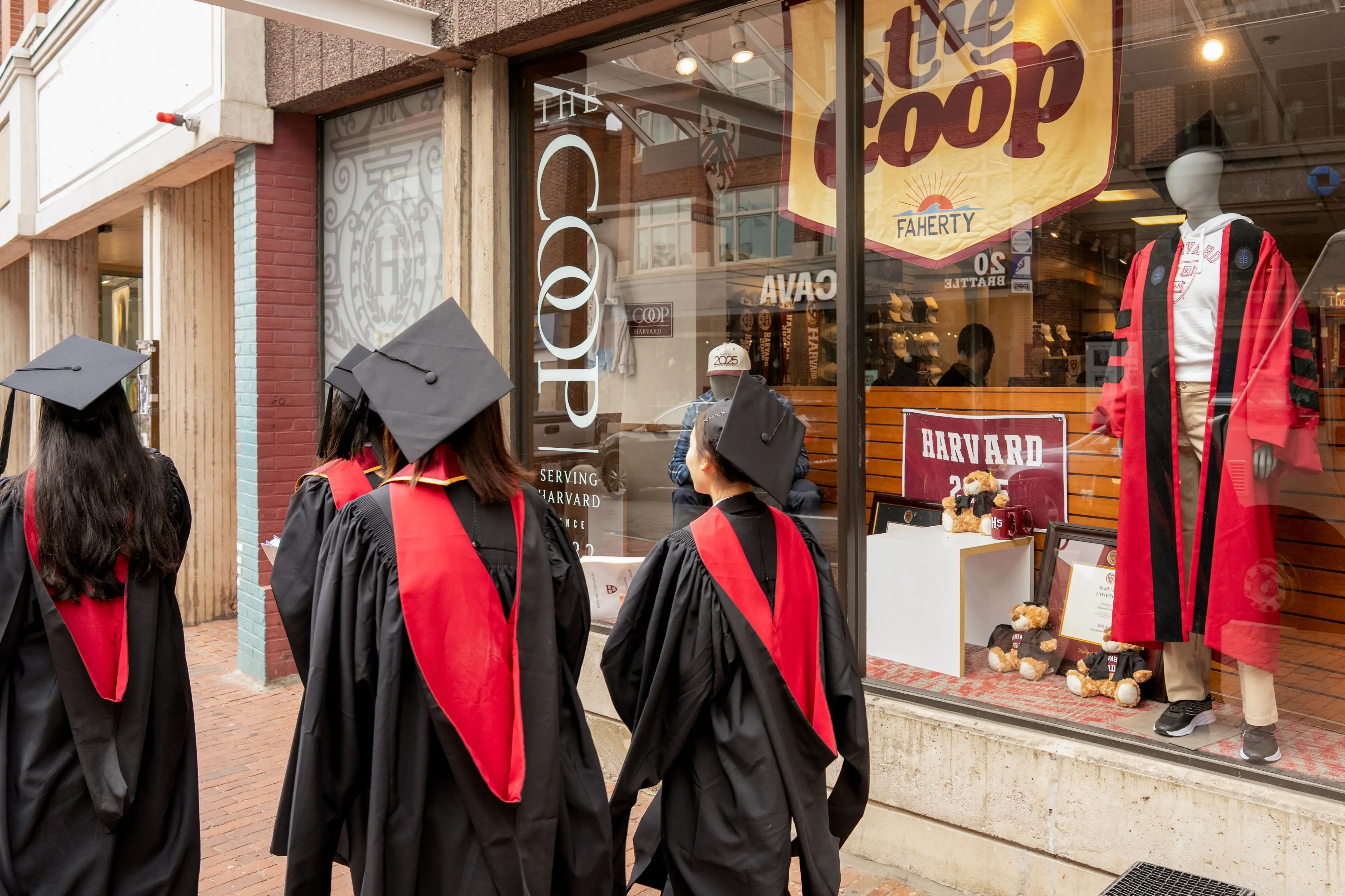 Harvard University students wearing graduation gowns walk past a bookstore near the Harvard University campus in Cambridge, Massachusetts, US, on Thursday, May 29, 2025.
