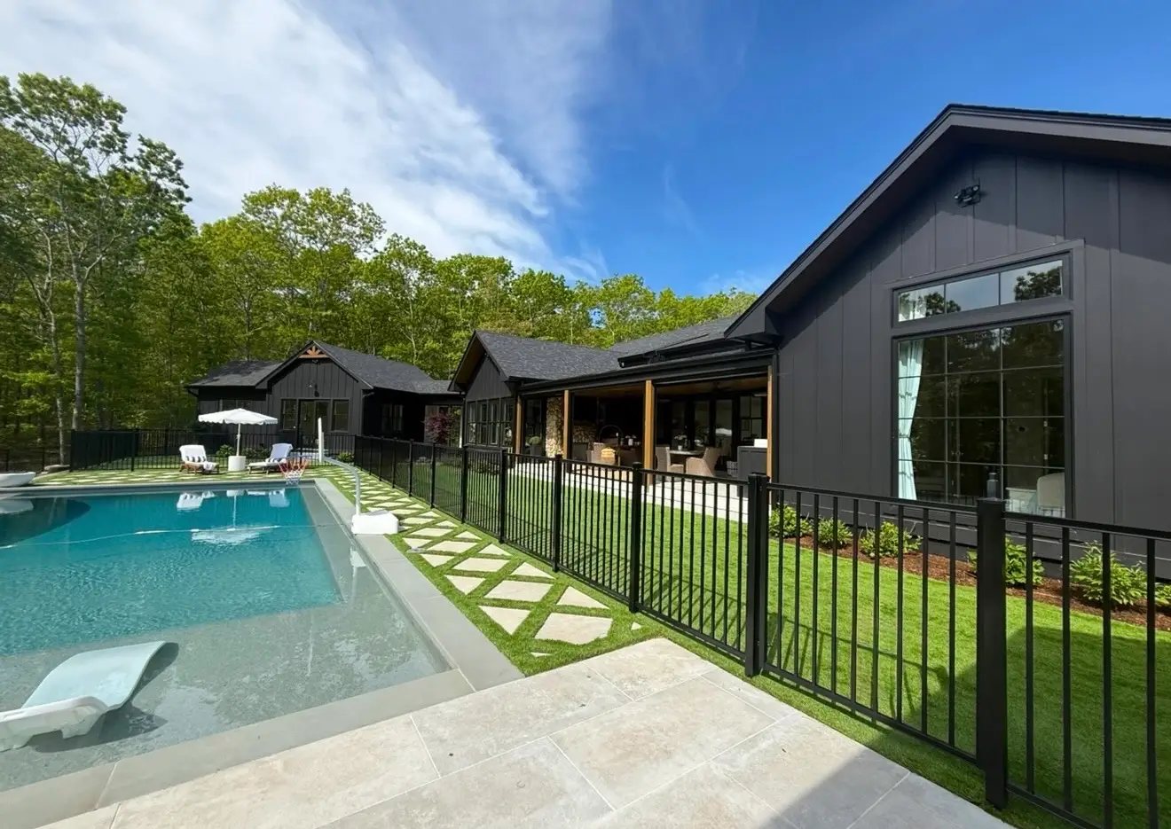 A gated pool outside of a large house.