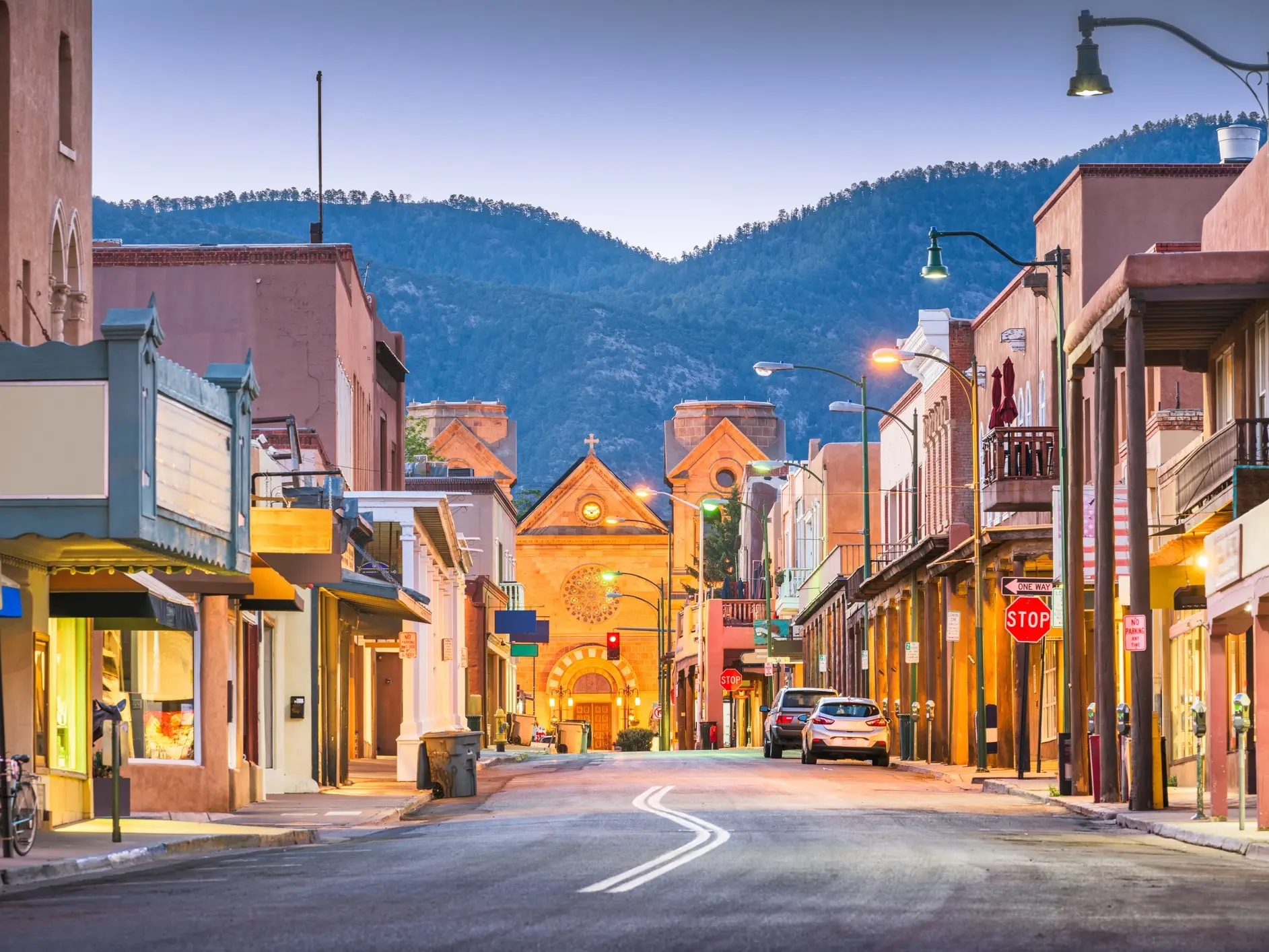 Santa Fe street at dusk leads to the illuminated Cathedral Basilica of St. Francis of Assisi.