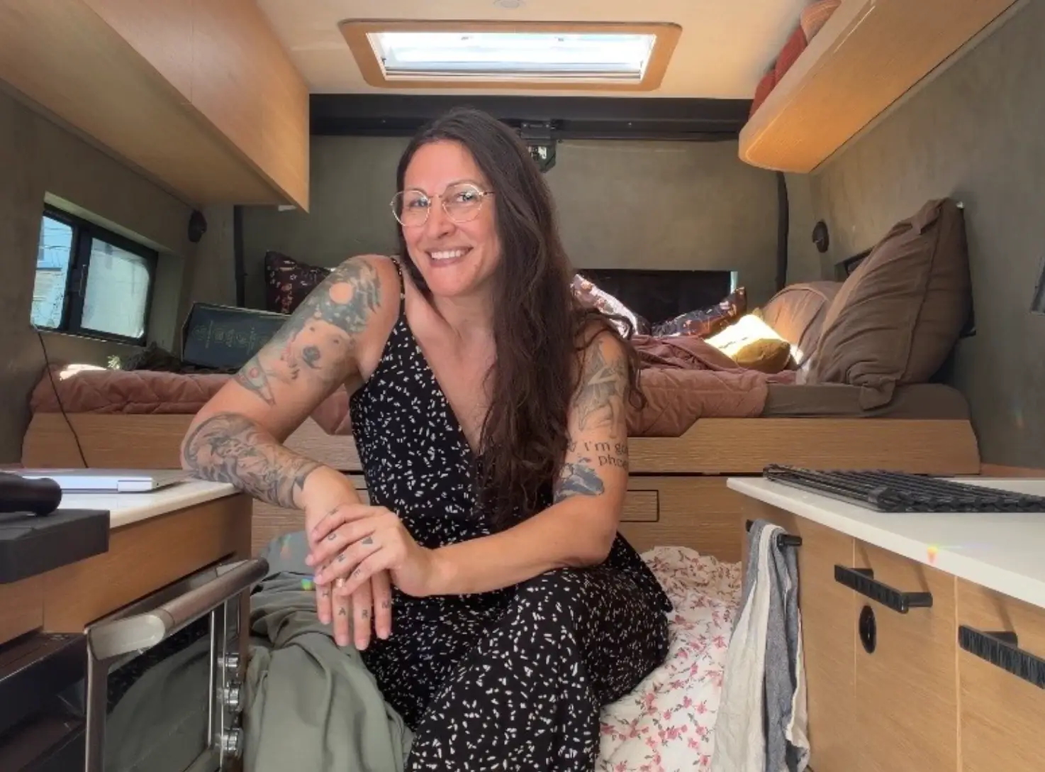 The writer sits on a pile of blankets inside her van.